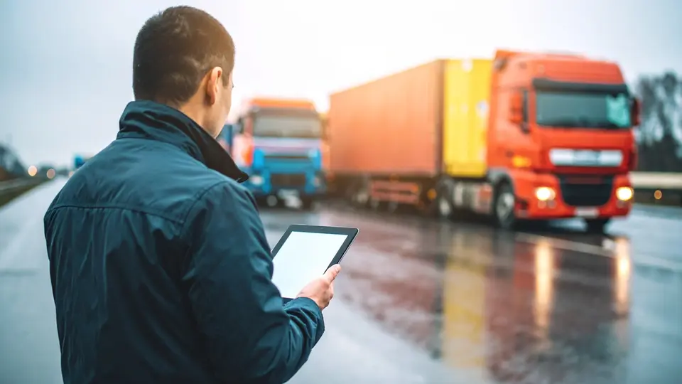 Man looking at an iPad in front of his truck fleet
