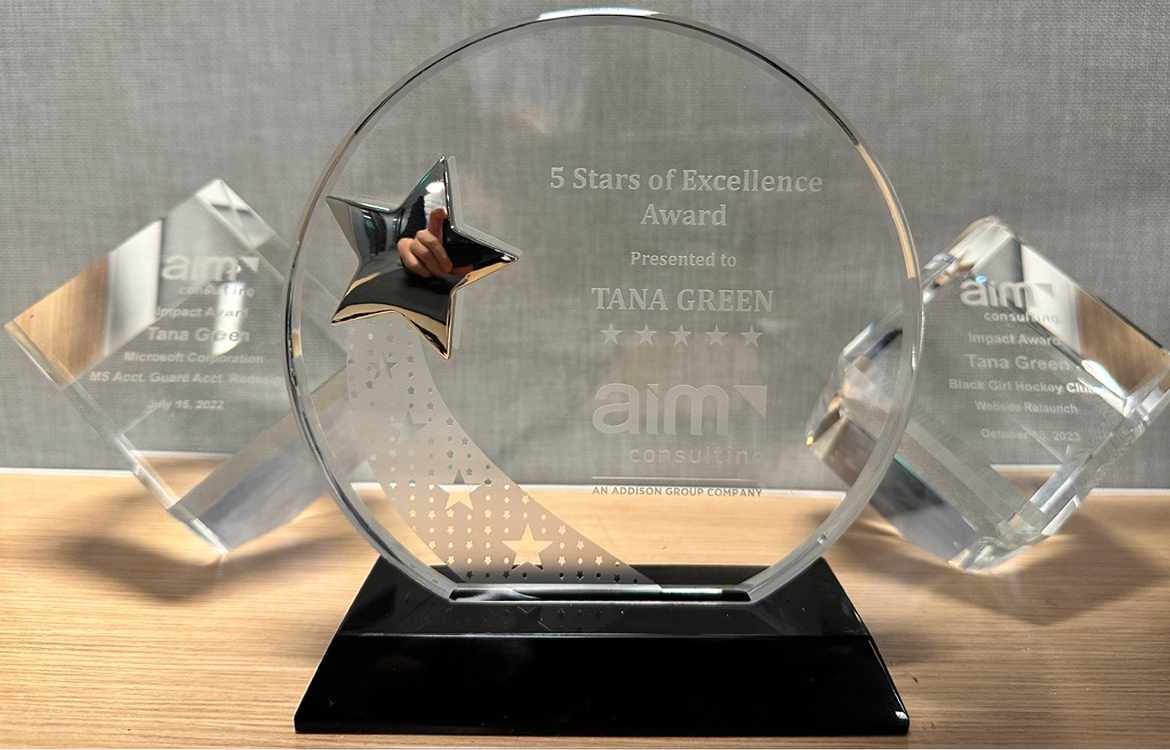 Three glass awards on a desk.
AIM's Five Stars of Excellence for Tana Green 2023 in the center. Impact Awards for Microsoft AccountGuard 2022 and Black Girl Hockey Club 2023