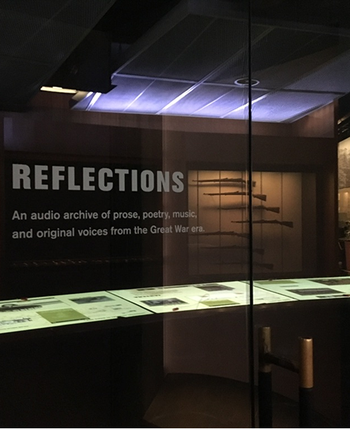 Darkened World War I museum gallery with an illuminated wall bearing the word Reflections