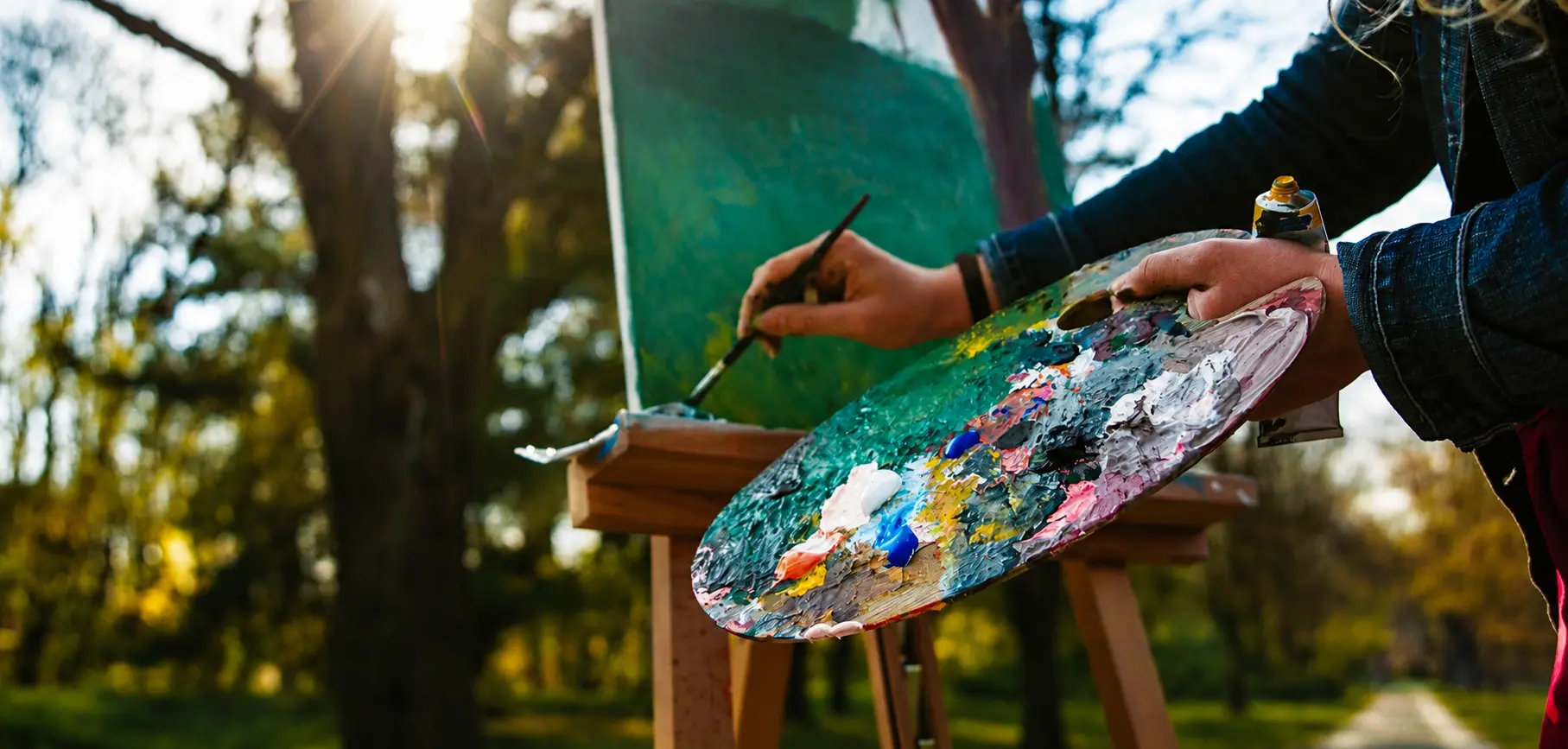 Woman painting using a pallet outside in the forest representing Studio Tour South Niagara Artists