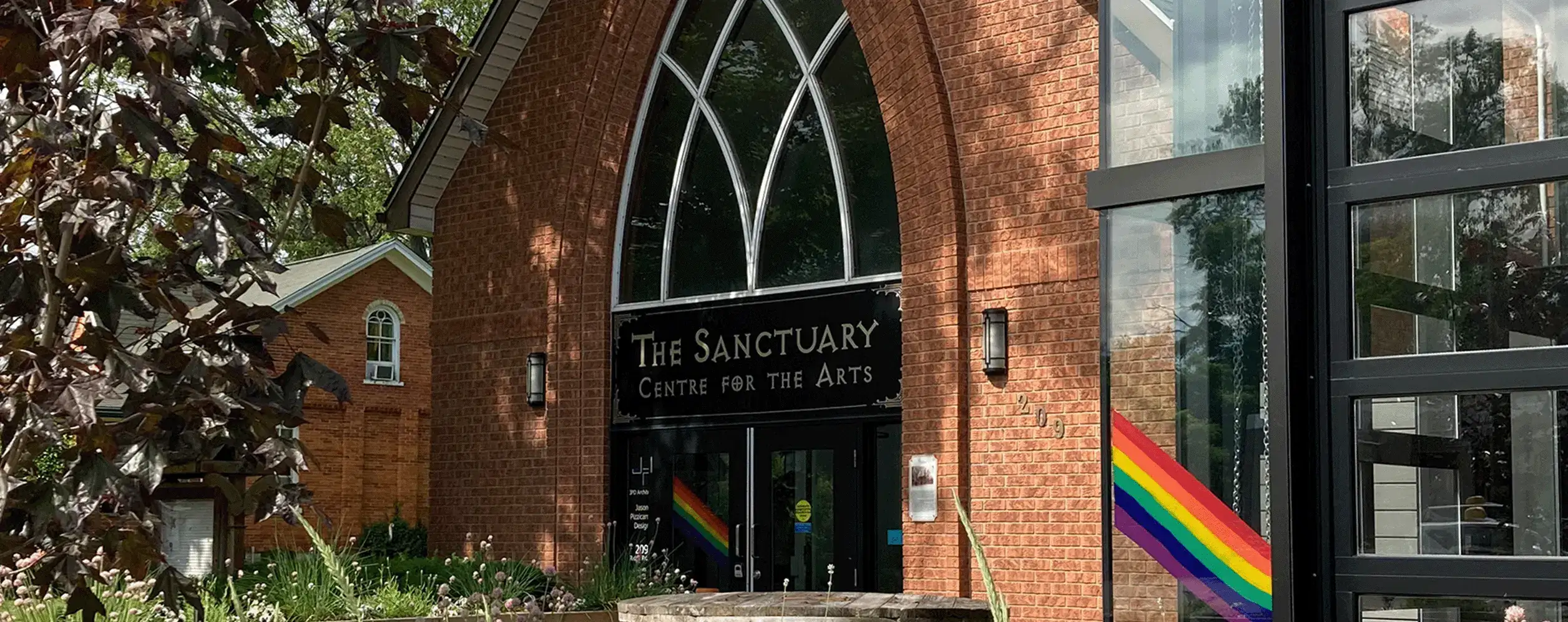 Outside of The Sanctuary Centre for the Arts building with sign, and brick building