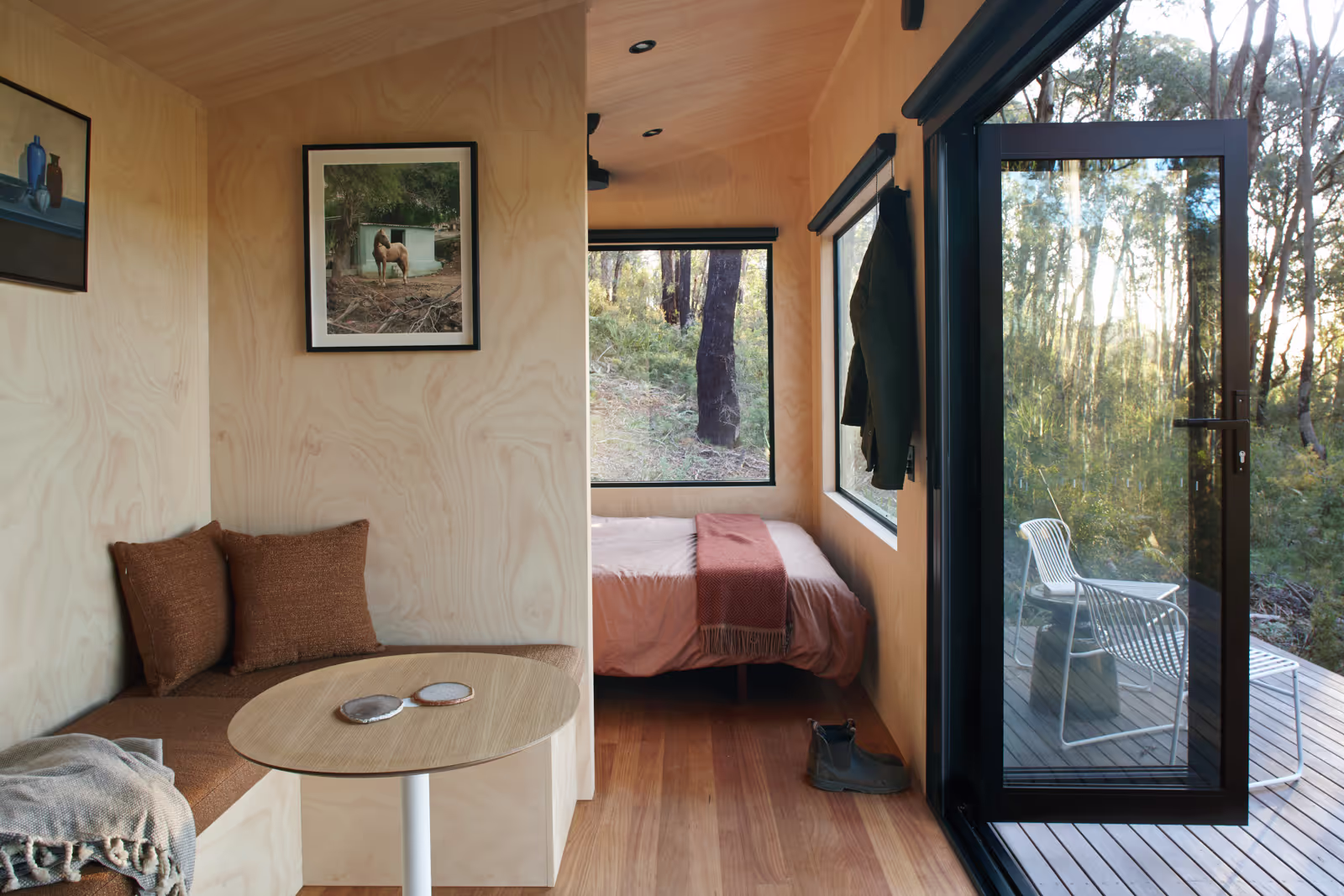 tall tiny house interiors looking out into the bush through large glass windows and folding doors