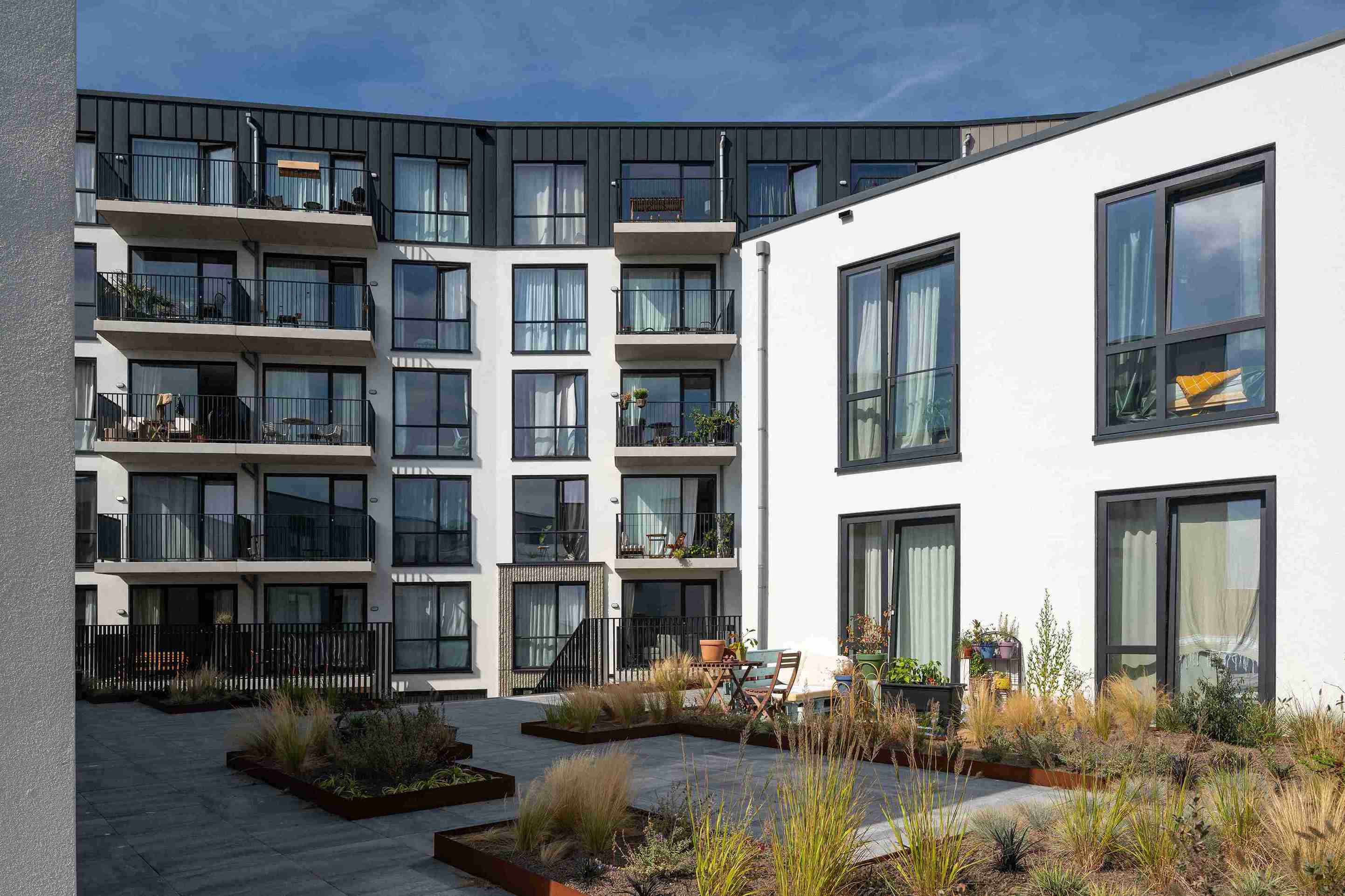 Achtergevel van een duurzaam woongebouw aan de Zeesluisweg, met een speels ritme van materialen en kleuren die verwijzen naar de architectuur van historisch Scheveningen.