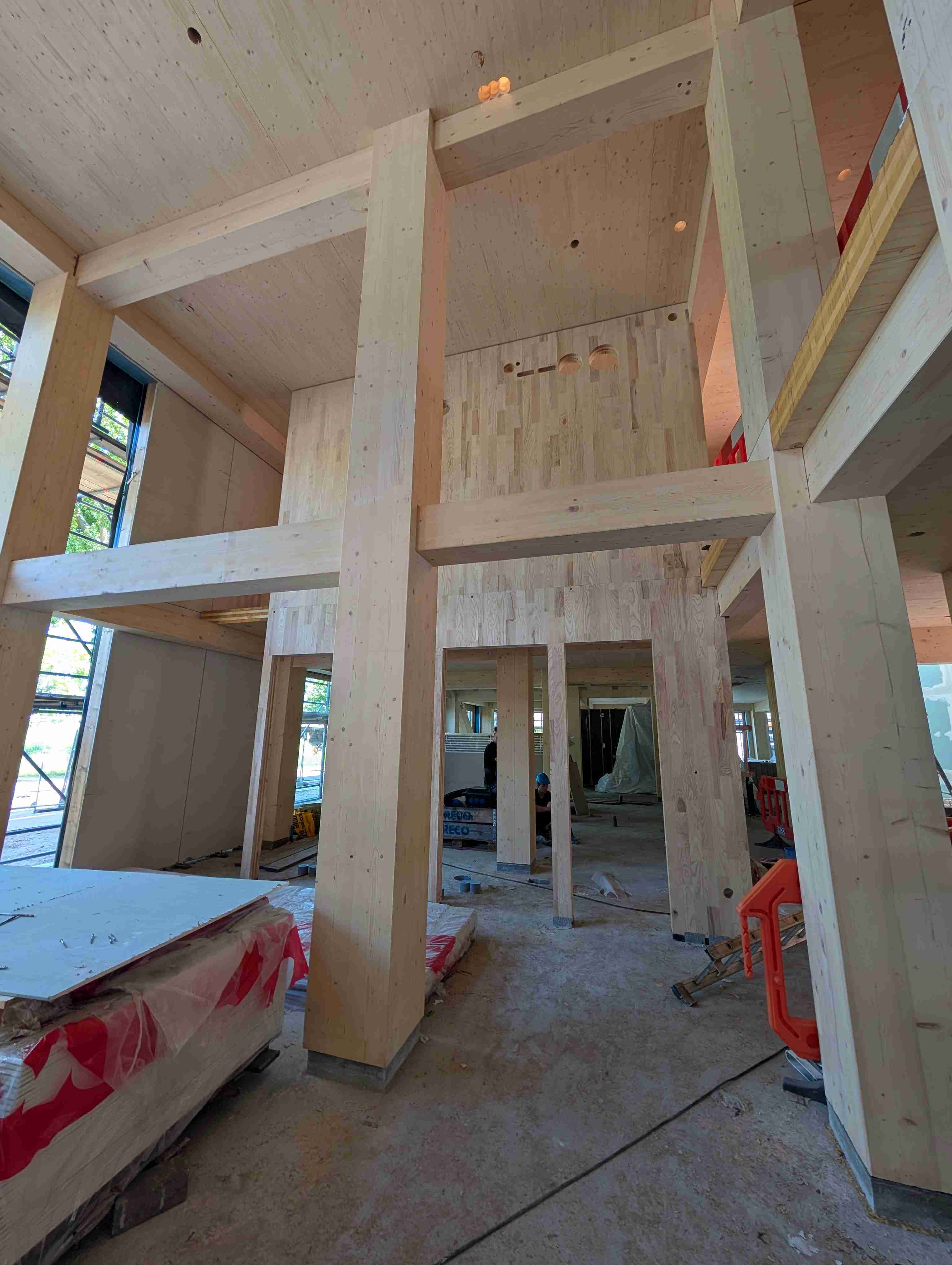 Constructief beeld van een houten ruwbouw waar C-CLT-panelen worden ingezet als tussenmuur, omgeven door grote CLT-kolommen en vloeren in een open gebouwstructuur.