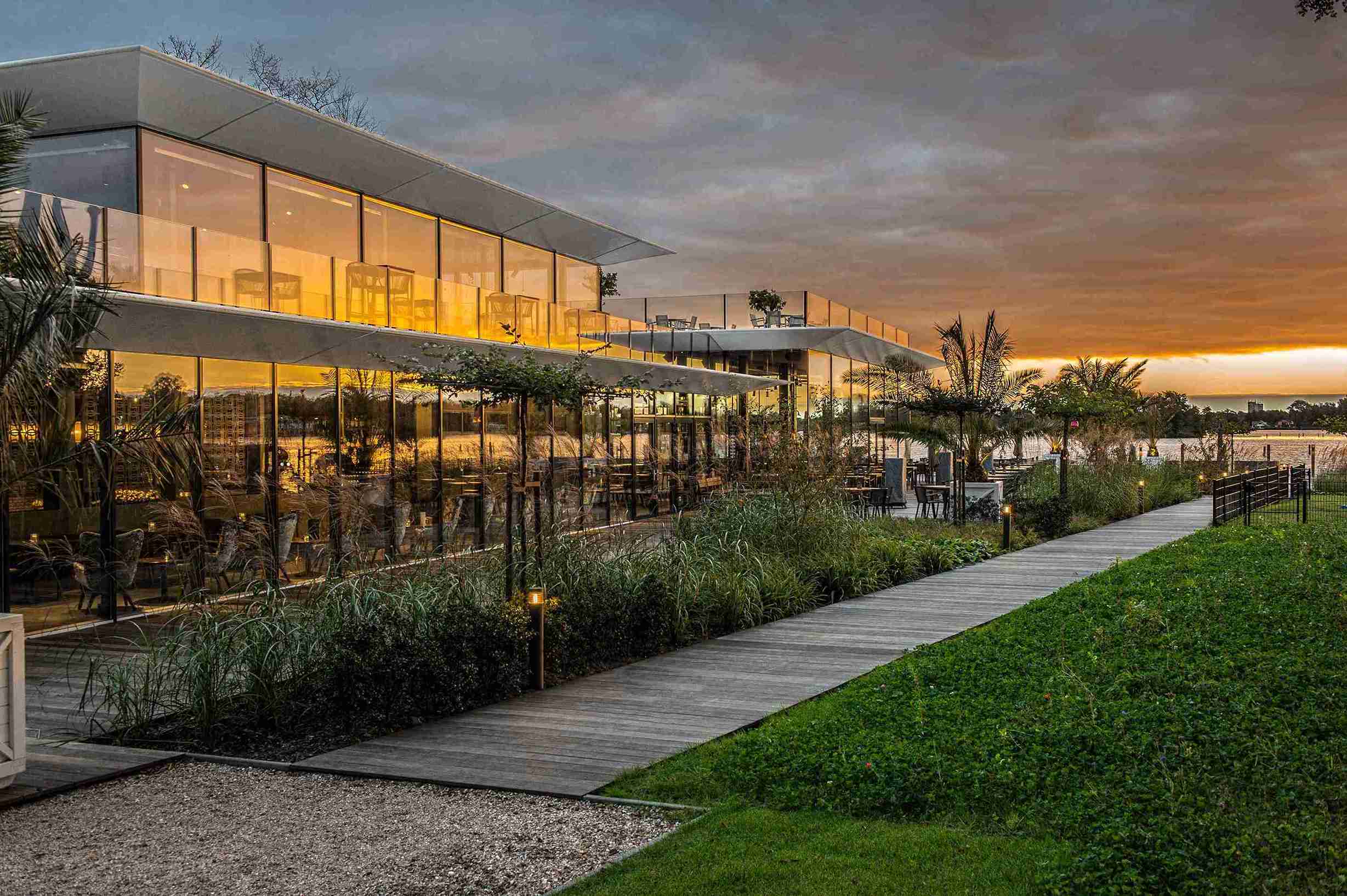 Transparante gevel van Paviljoen De Dame biedt wijds uitzicht op natuur rondom Paterswolde, waar interieur en landschap samenvloeien.