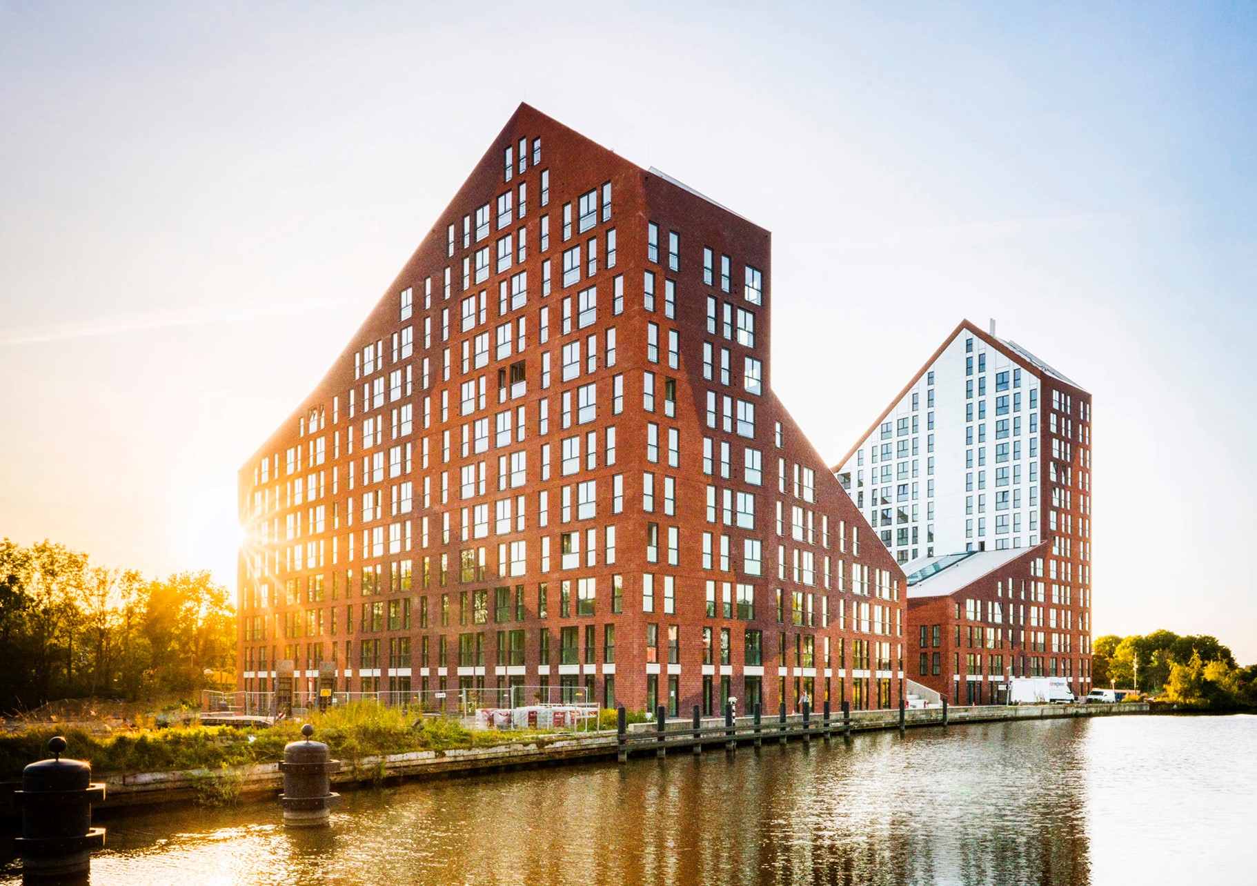 Stedelijk woongebouw aan het water met expressieve baksteenarchitectuur en duurzame woningbouw in Nederland tijdens zonsondergang
