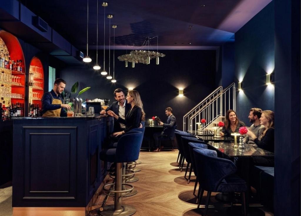 Sfeervolle hotelbar van Hotel Fluwelen Burgwal in Den Haag met donkerblauw interieur en houten vloer