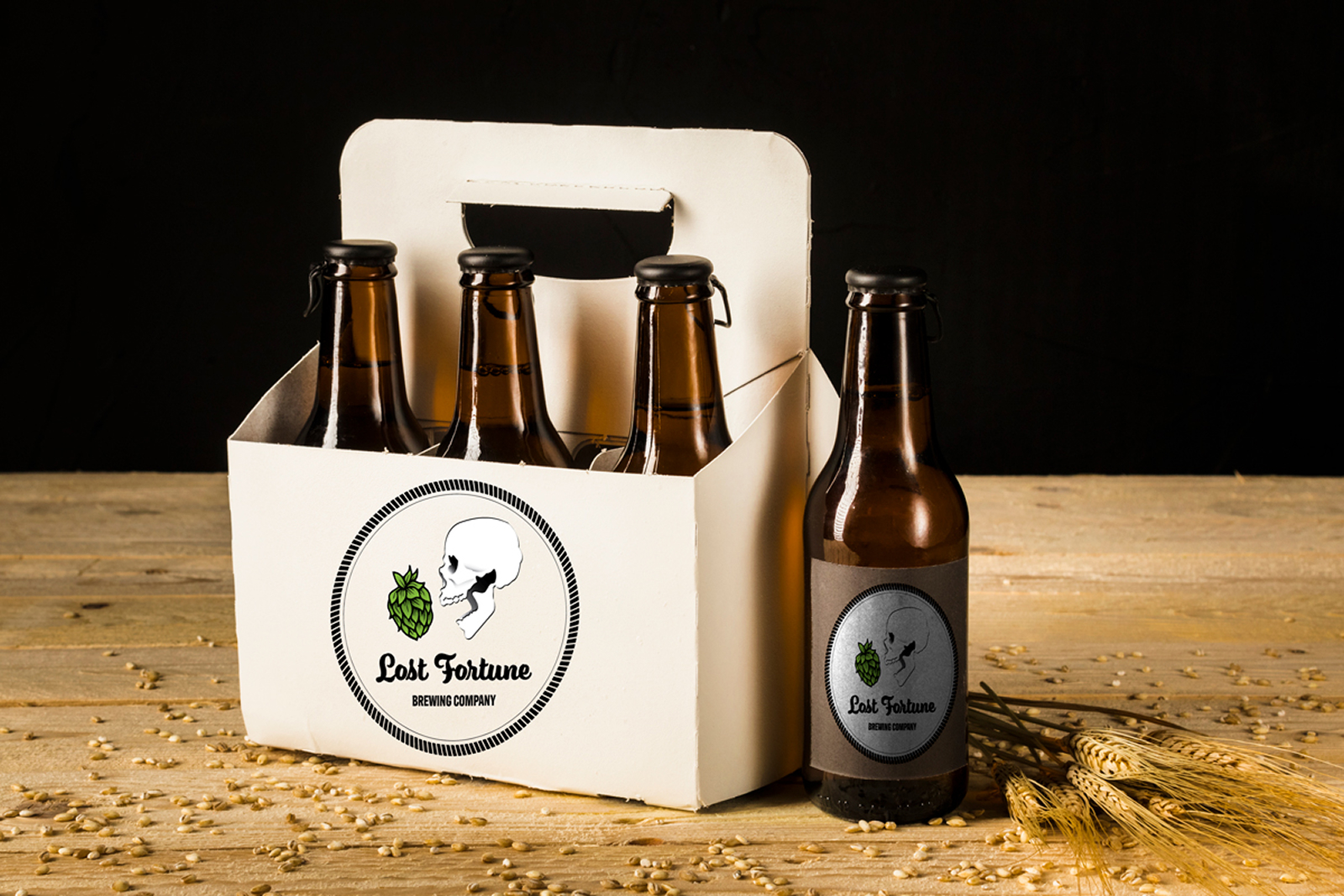 Four brown beer bottles in a white carrier and one bottle beside it with Lost Fortune Brewing Company label.