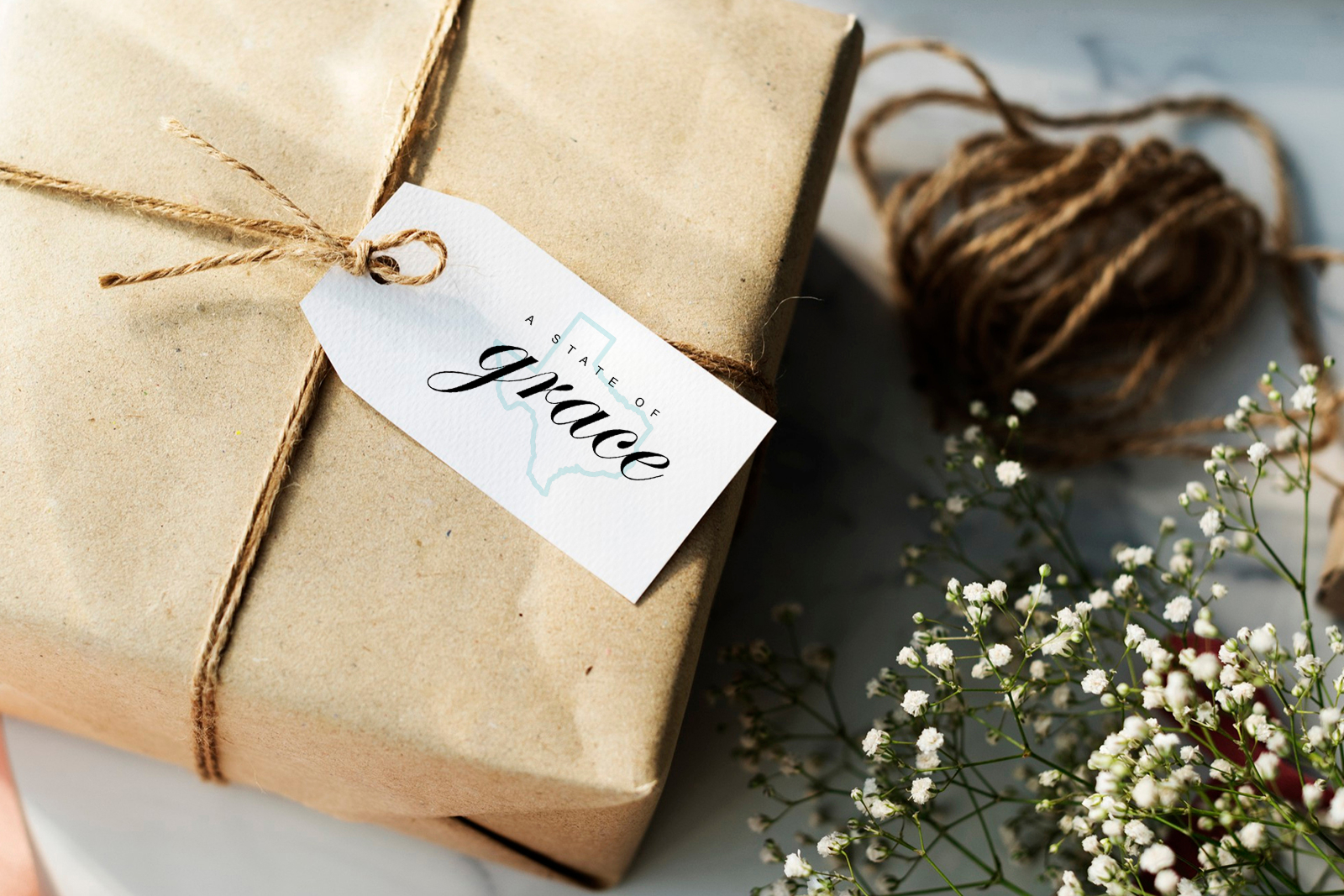 Gift wrapped in brown paper with twine and a tag reading 'A state of grace' with Texas outline.