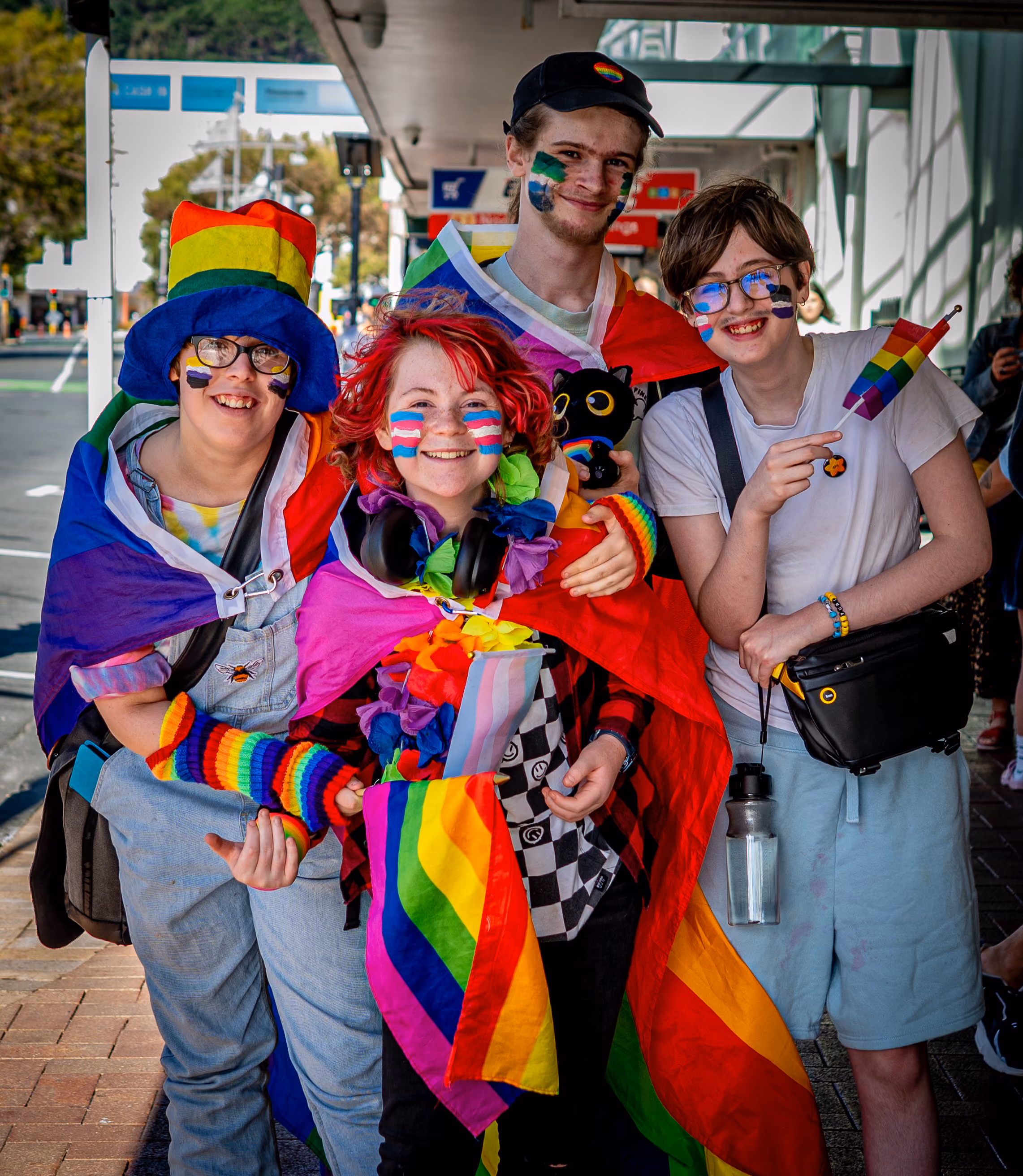 A group of parade-goers wrapped in rainbow flags