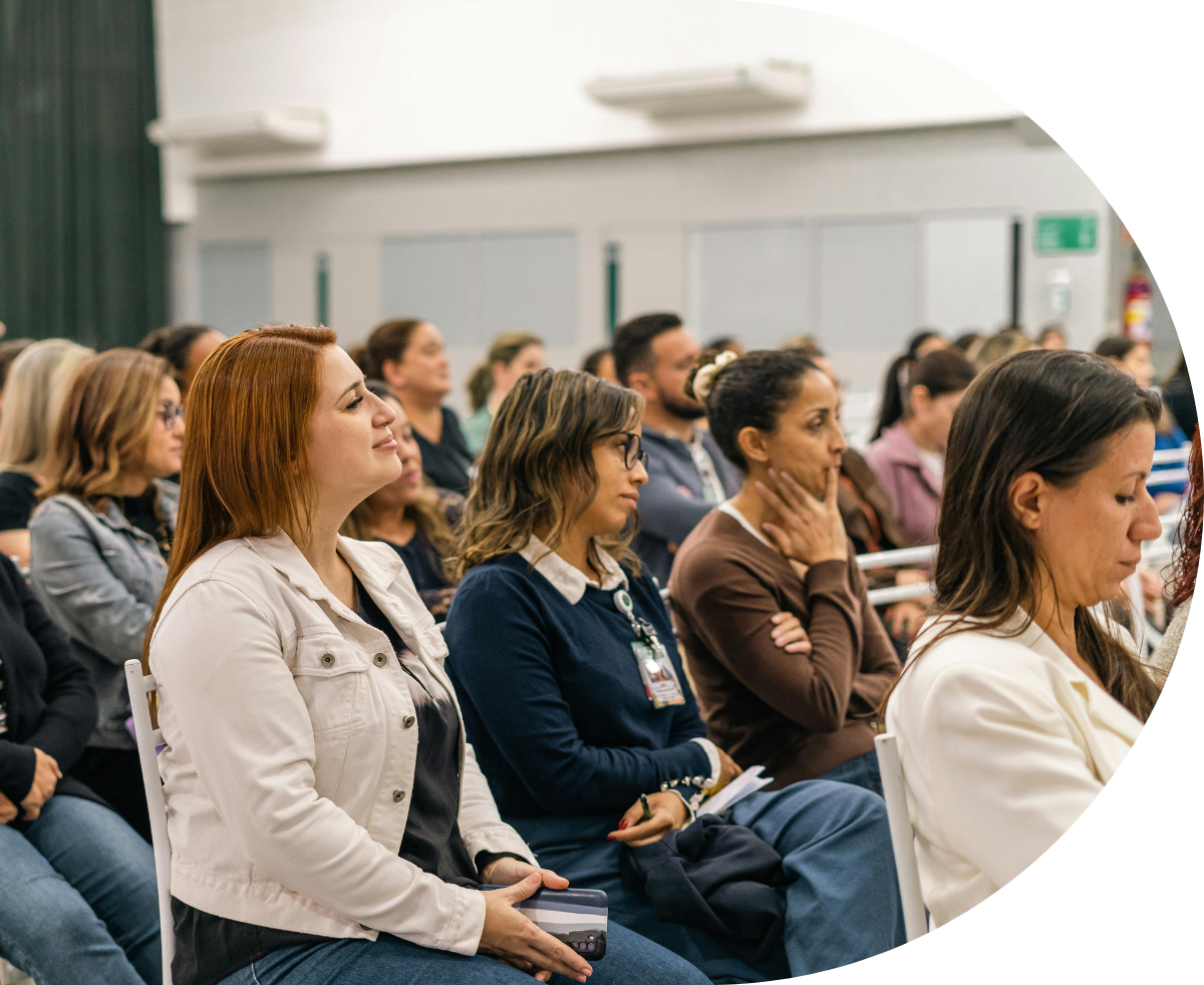 Professionals intently listening at a conference, taking notes on notepads