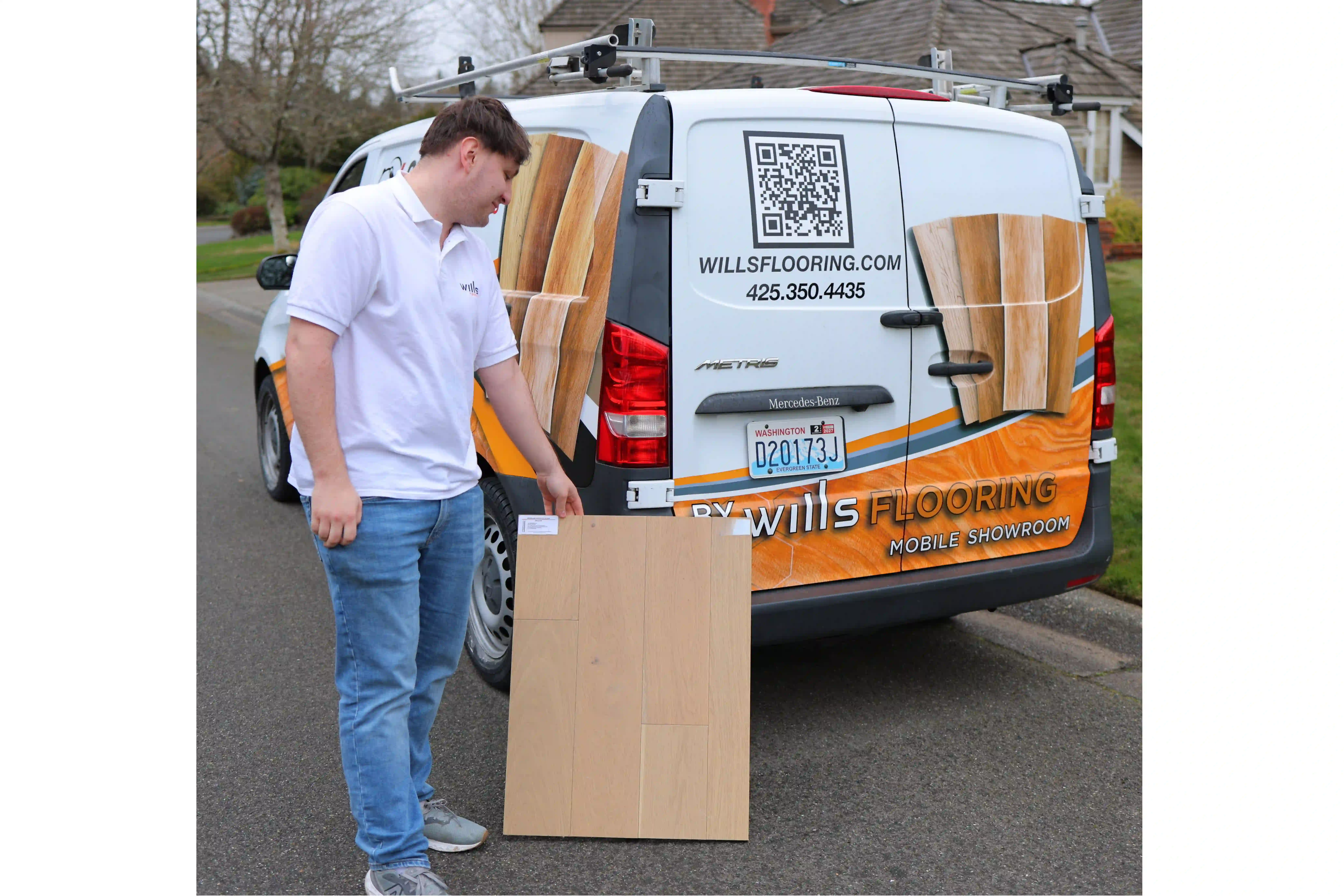Wills Flooring team member showing hardwood samples beside the mobile flooring showroom van