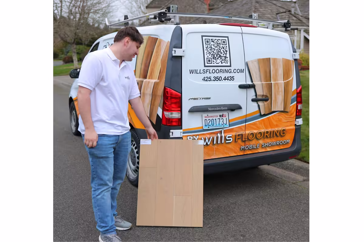Wills Flooring team member showing hardwood samples beside the mobile flooring showroom van