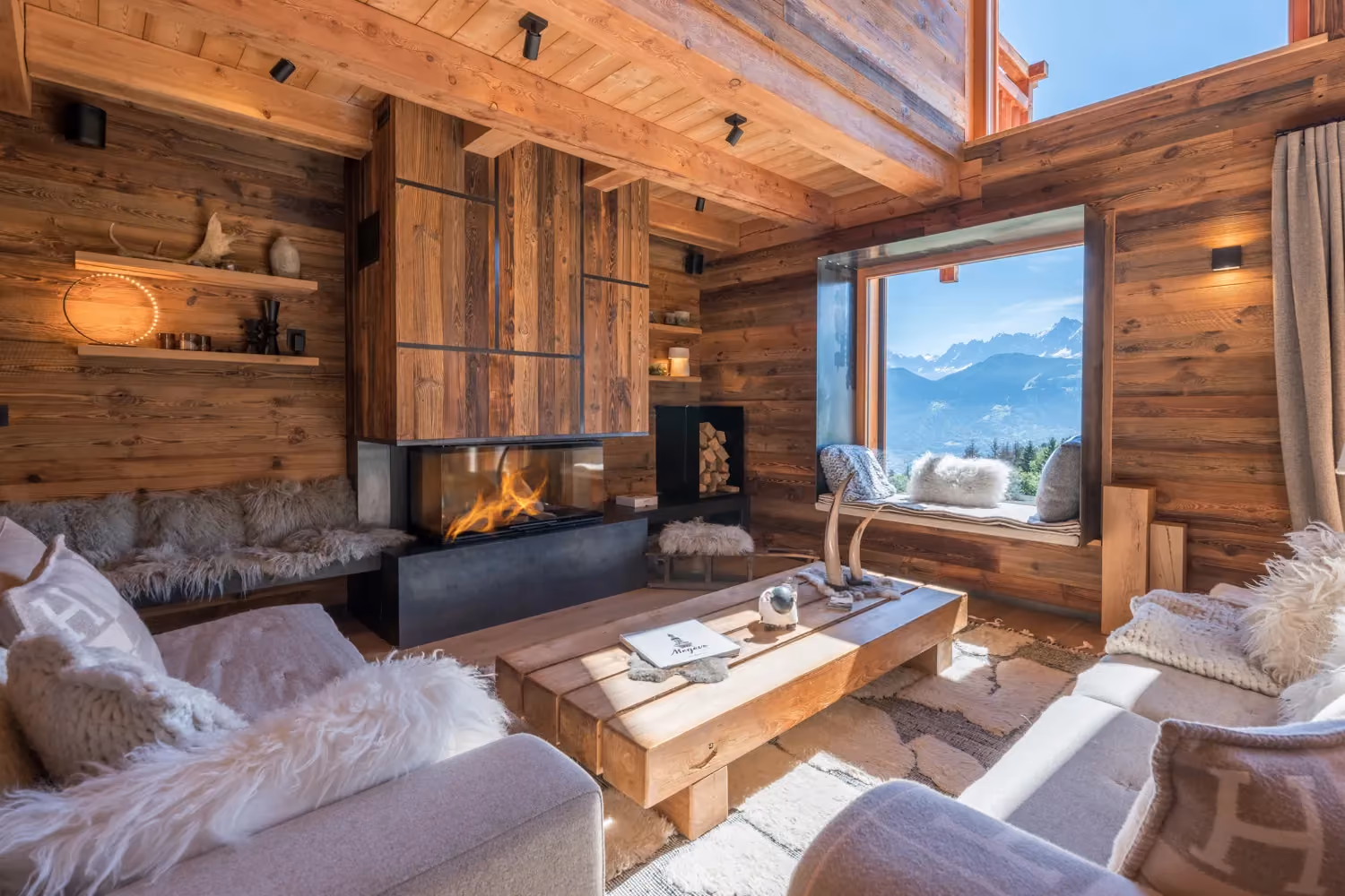 Cosy living room with fireplace and panoramic Mont Blanc views in a luxury chalet in Megève.