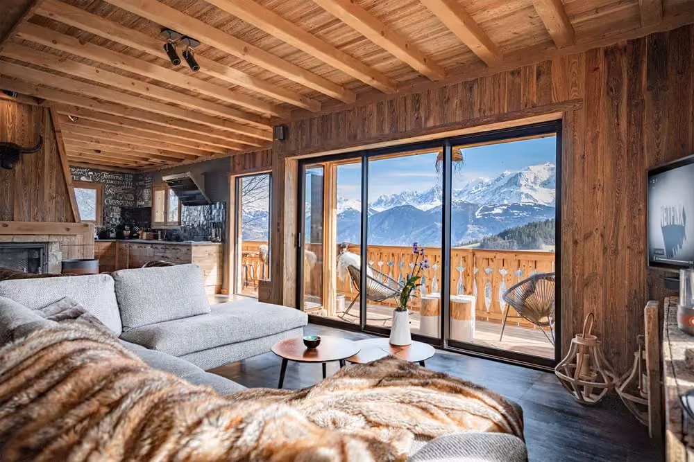 Salon chaleureux avec cheminée et grandes baies vitrées dans un chalet de luxe à Cordon.