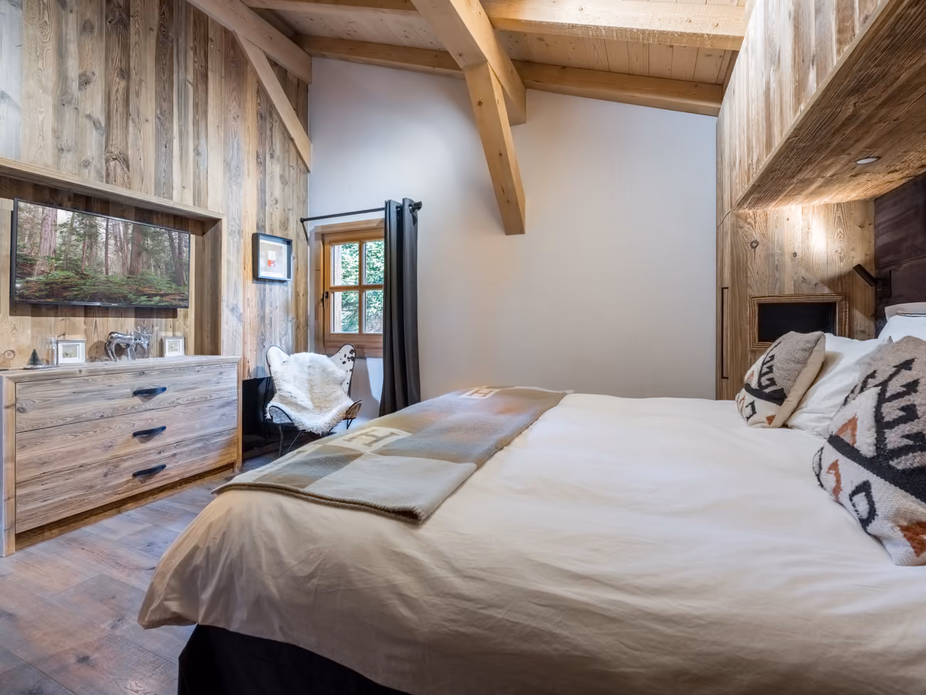 Cozy double bedroom with TV and reclaimed wood décor in a luxury chalet