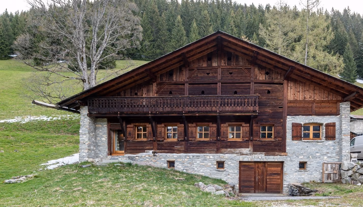 Façade d'un chalet traditionnel savoyard entouré de nature à Megève.
