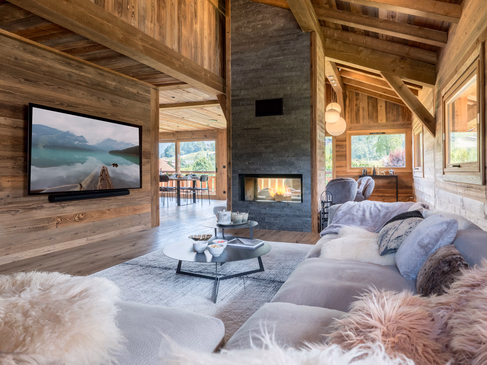 Cosy living room with a contemporary fireplace and large sofas at Chalet Double M in Combloux overlooking Mont Blanc.
