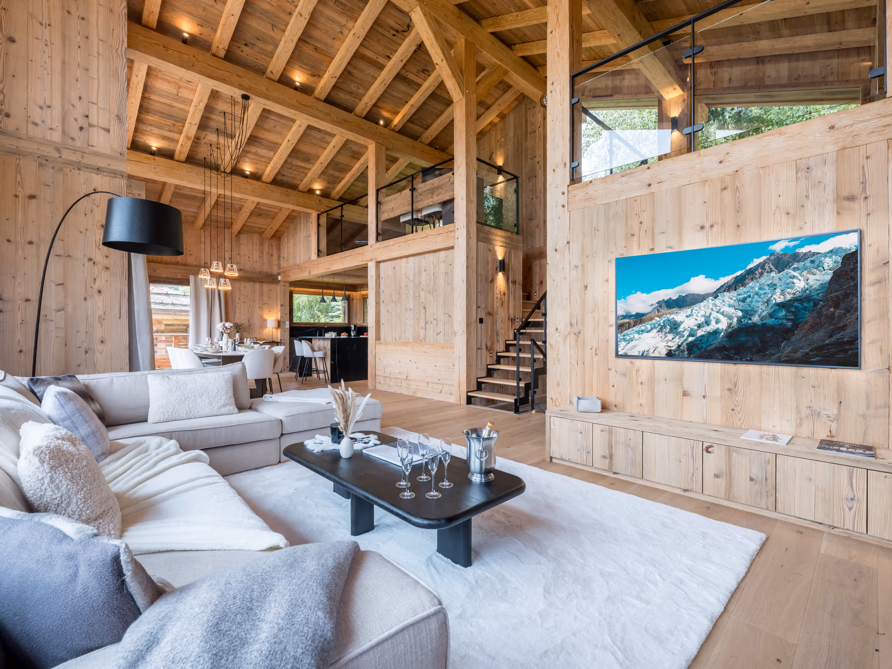 Bright open-plan living space with lounge, dining area and mezzanine at Chalet Victory in Combloux.