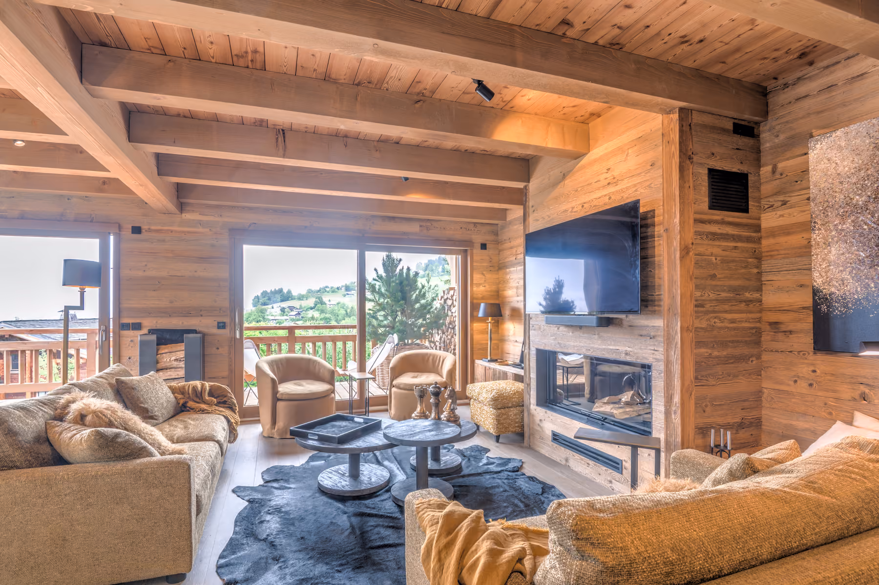 Salon chaleureux avec cheminée, télévision et accès au balcon au Chalet Black Eagle à Combloux.