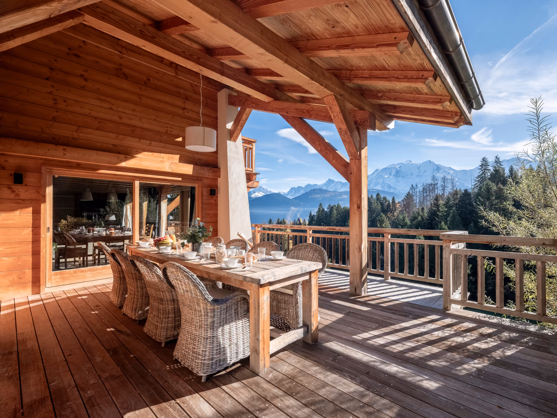 Spacious wooden terrace with outdoor dining area and panoramic views of the Mont Blanc massif in Combloux.