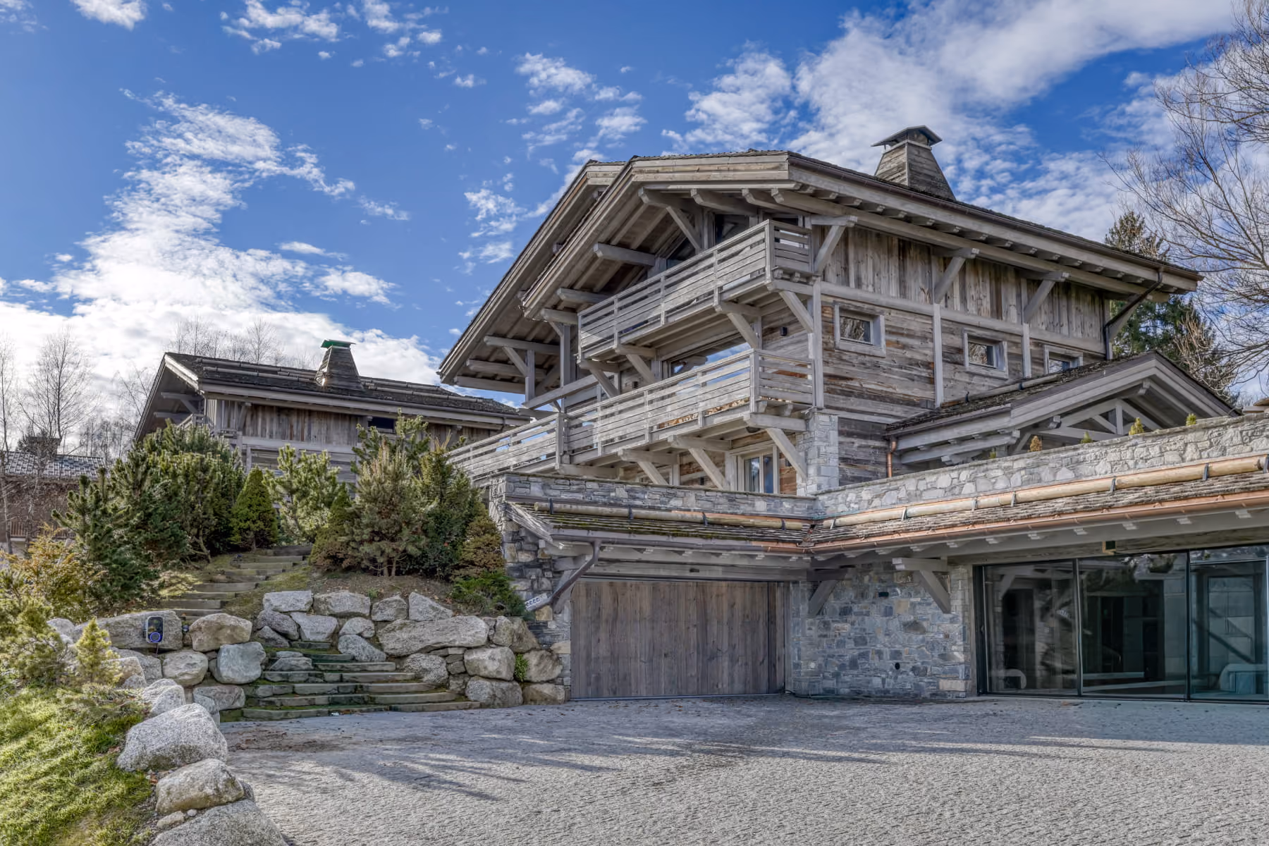 Exterior of a luxury alpine chalet with balconies, garage and traditional mountain architecture.