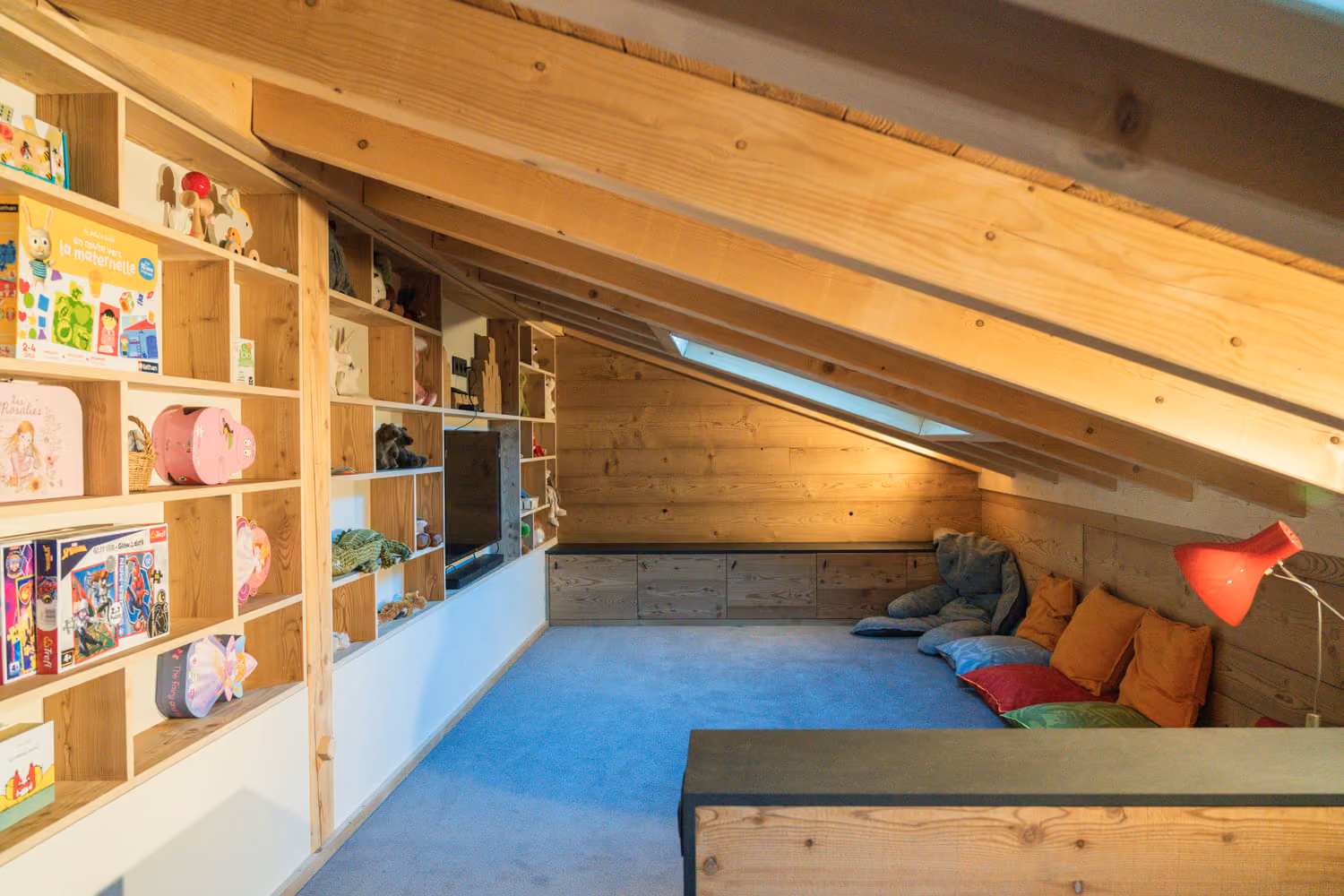 Children's playroom with bookshelves, TV and cozy relaxation area beneath the eaves.