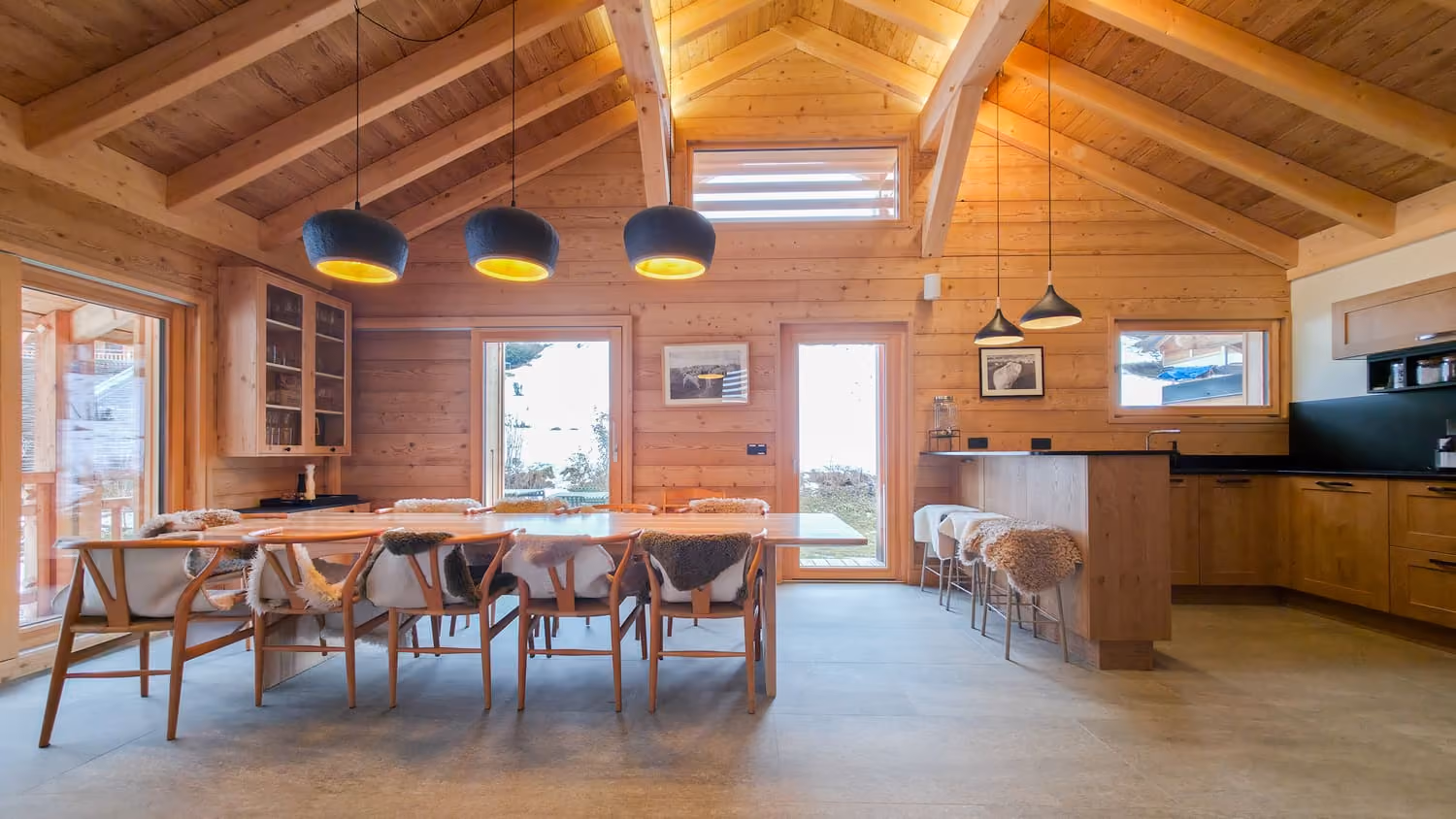 Inviting dining area with open-plan kitchen and vaulted ceiling in an Alpine chalet.