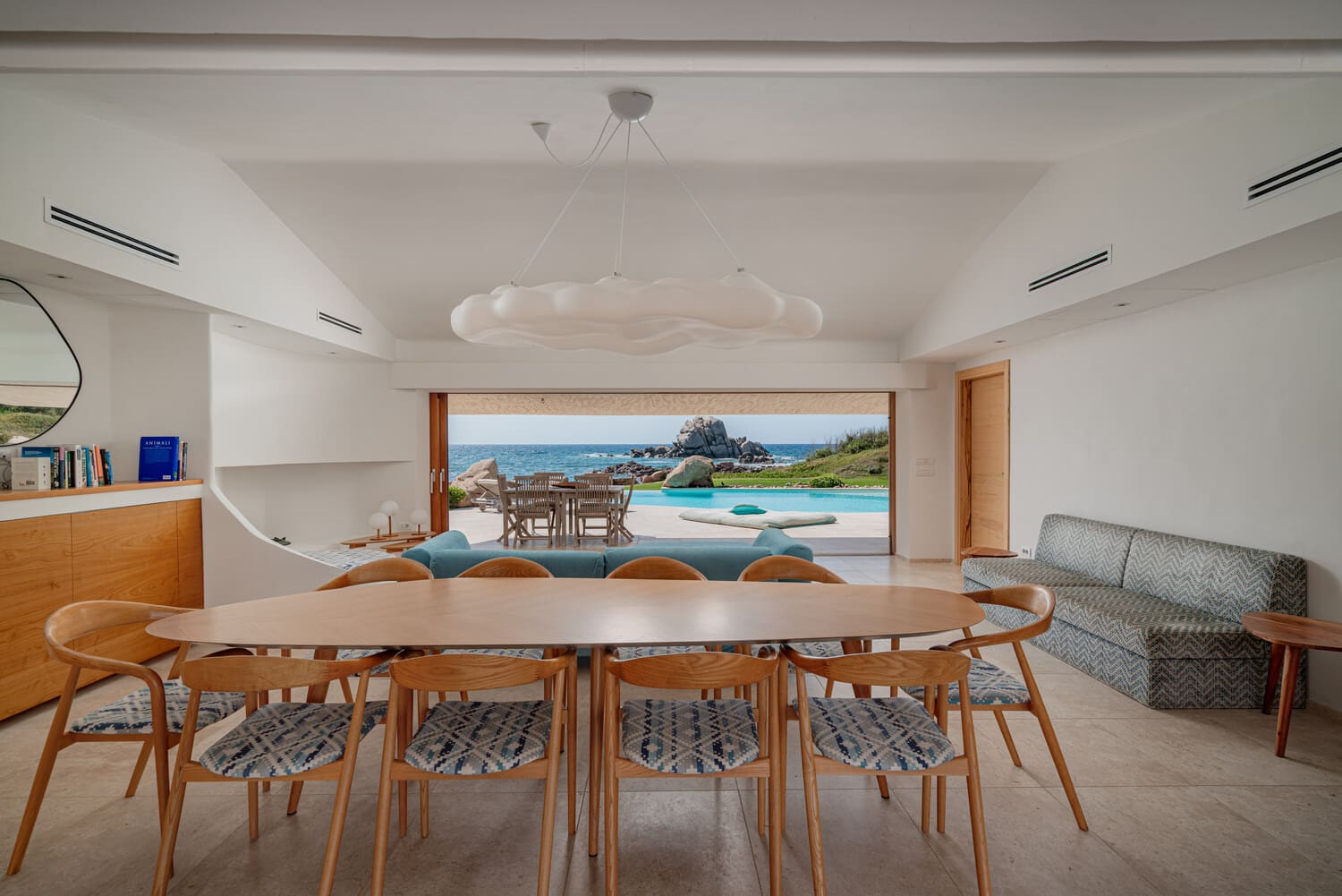 Pièce de vie ouverte avec vue sur la piscine et la mer dans une villa de luxe en Sardaigne.