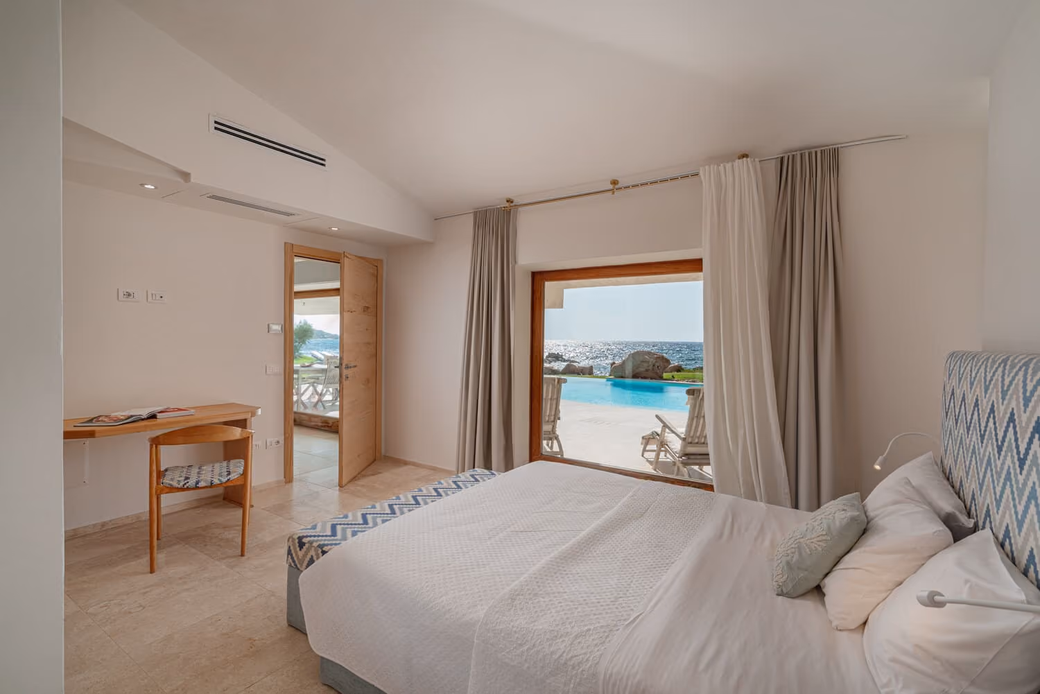 Bedroom with direct access to the terrace, pool and sea views in a luxury villa in Sardinia.