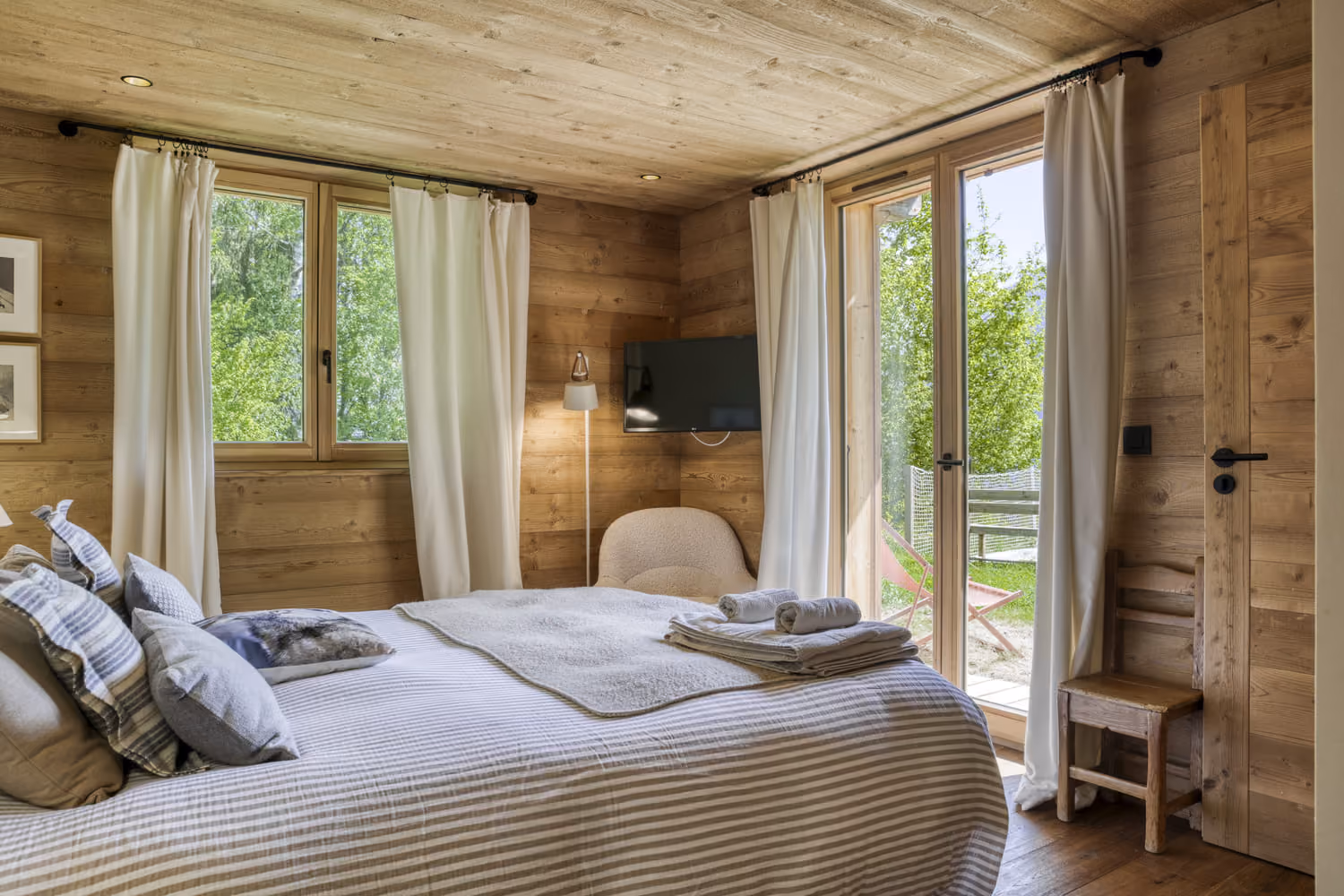Cozy double bedroom with private terrace and nature views in a luxury mountain chalet.
