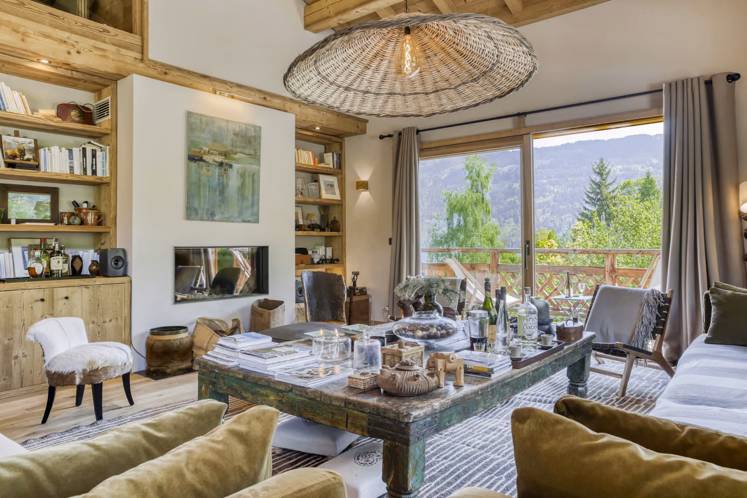 Elegant living room with fireplace, library and large windows overlooking the mountains.