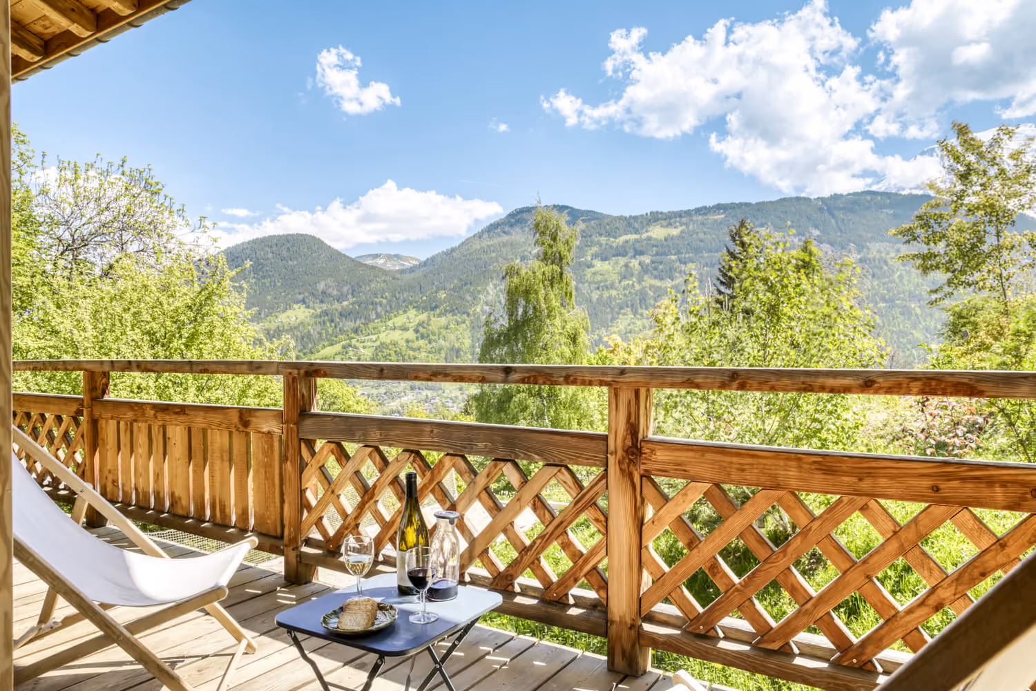 Wooden terrace with panoramic mountain views, perfect for relaxing during summer.