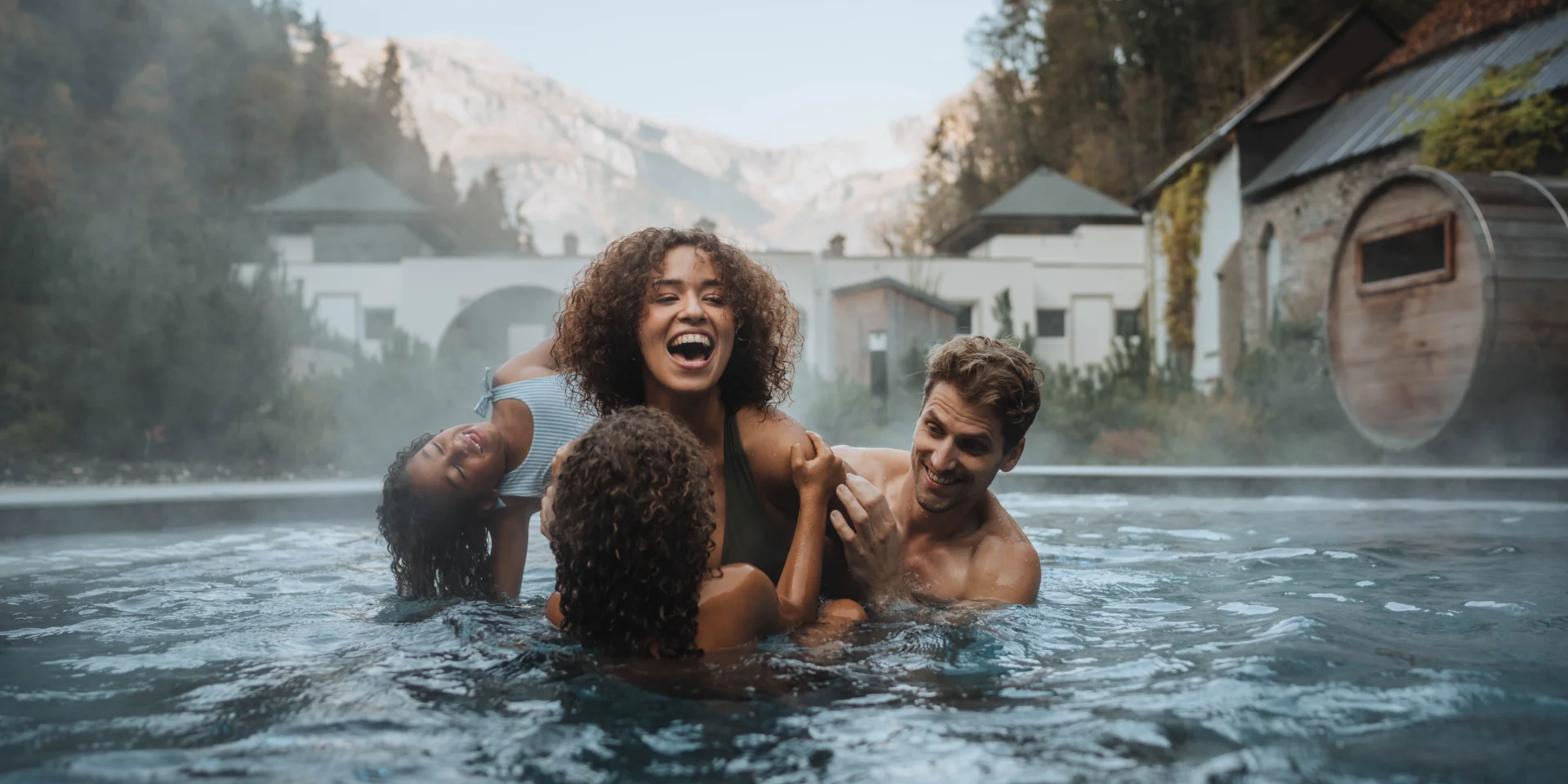 Famille profitant des bassins extérieurs des Thermes de Saint-Gervais Mont-Blanc face aux montagnes.