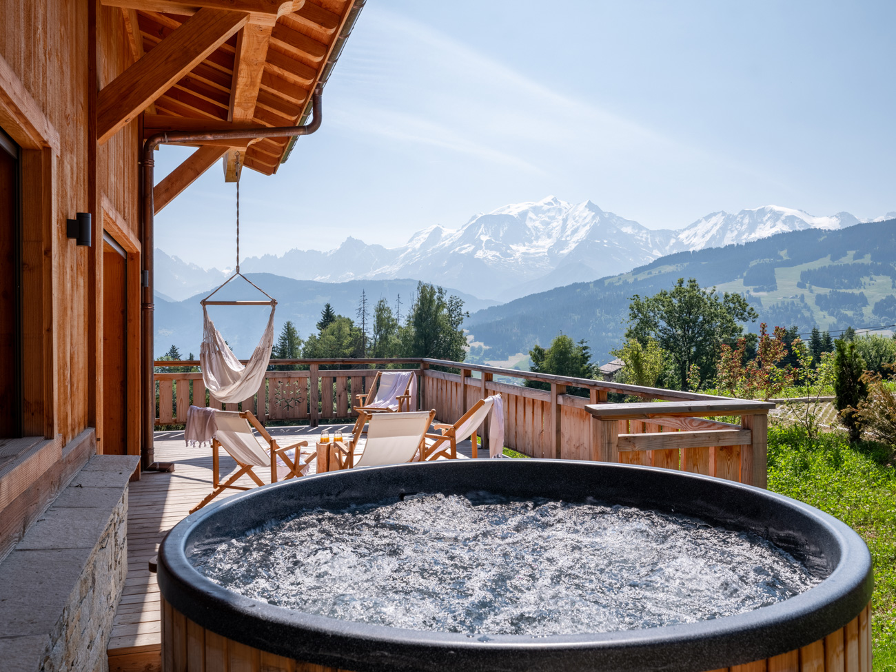 Jacuzzi extérieur sur la terrasse d’un chalet avec vue panoramique sur le Mont-Blanc.