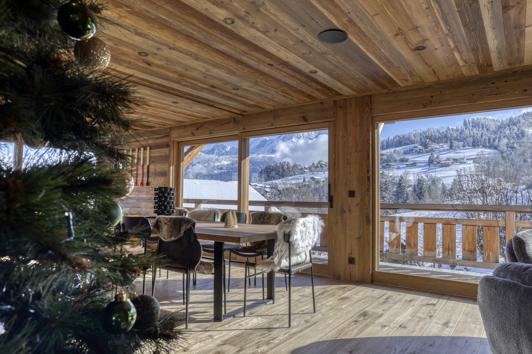Salle à manger d’un chalet décoré pour Noël avec vue sur les montagnes enneigées