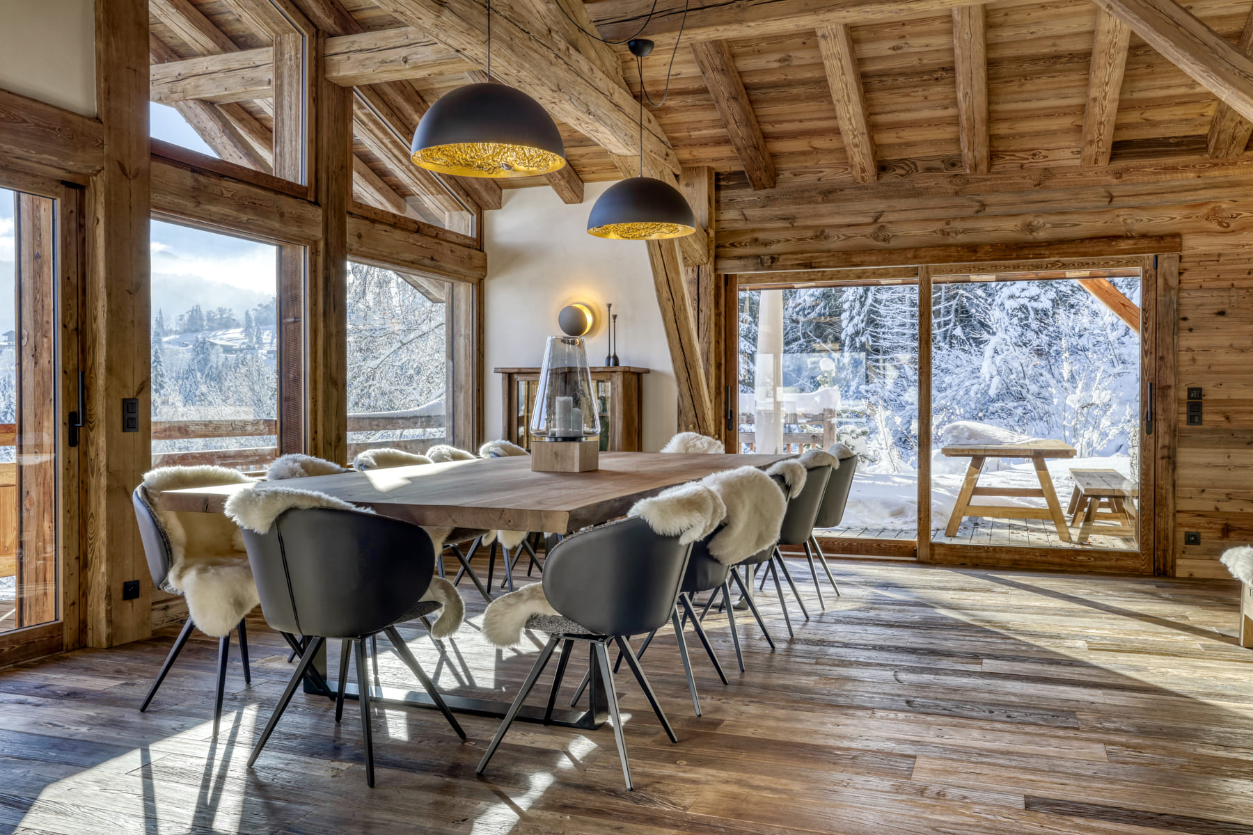 Salle à manger chaleureuse d’un chalet de montagne avec terrasse et paysage enneigé