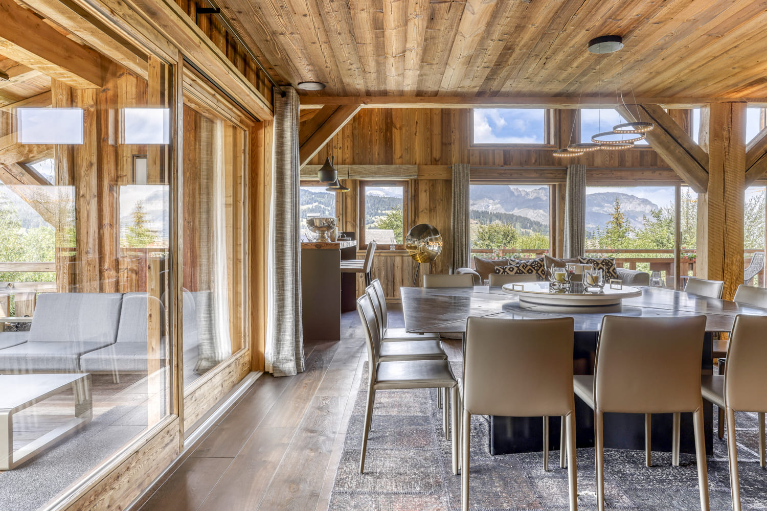 Grande salle à manger d’un chalet à Megève avec baies vitrées et vue sur les montagnes
