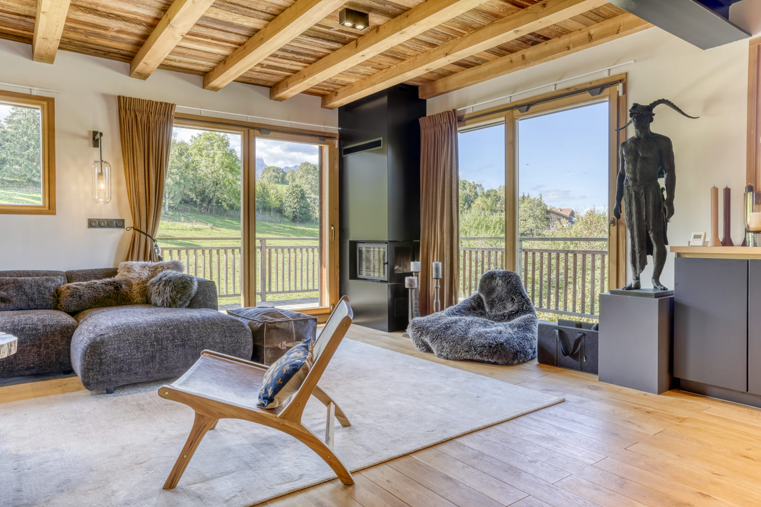 Salon avec cheminée et grandes baies vitrées au Chalet Karuna à Combloux
