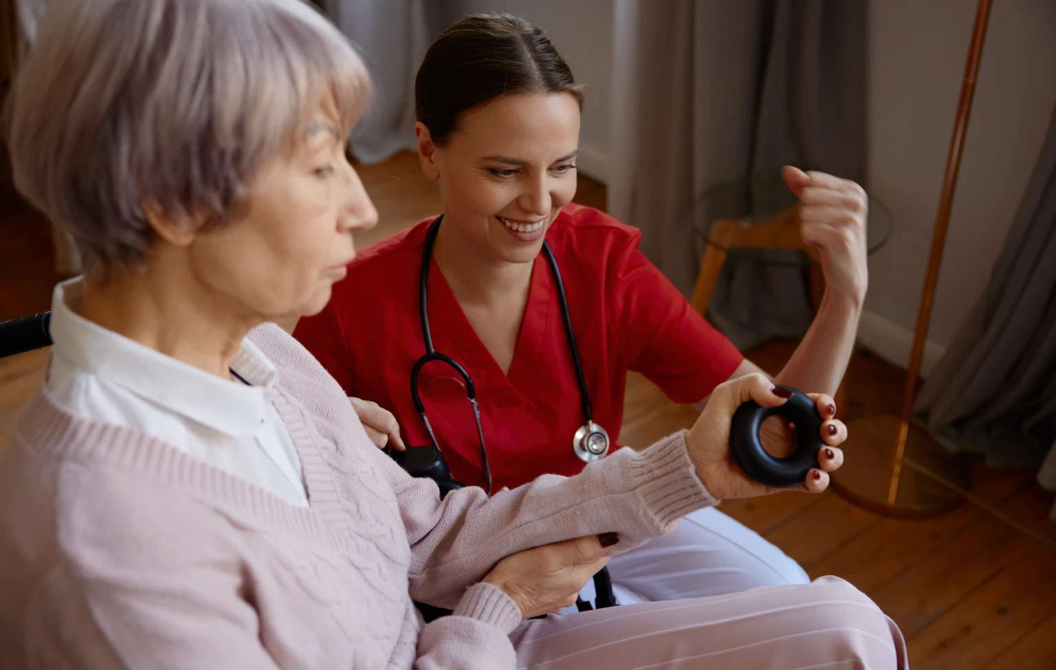Occupational therapy student assisting an older adult with a hand-strength exercise during clinical fieldwork.