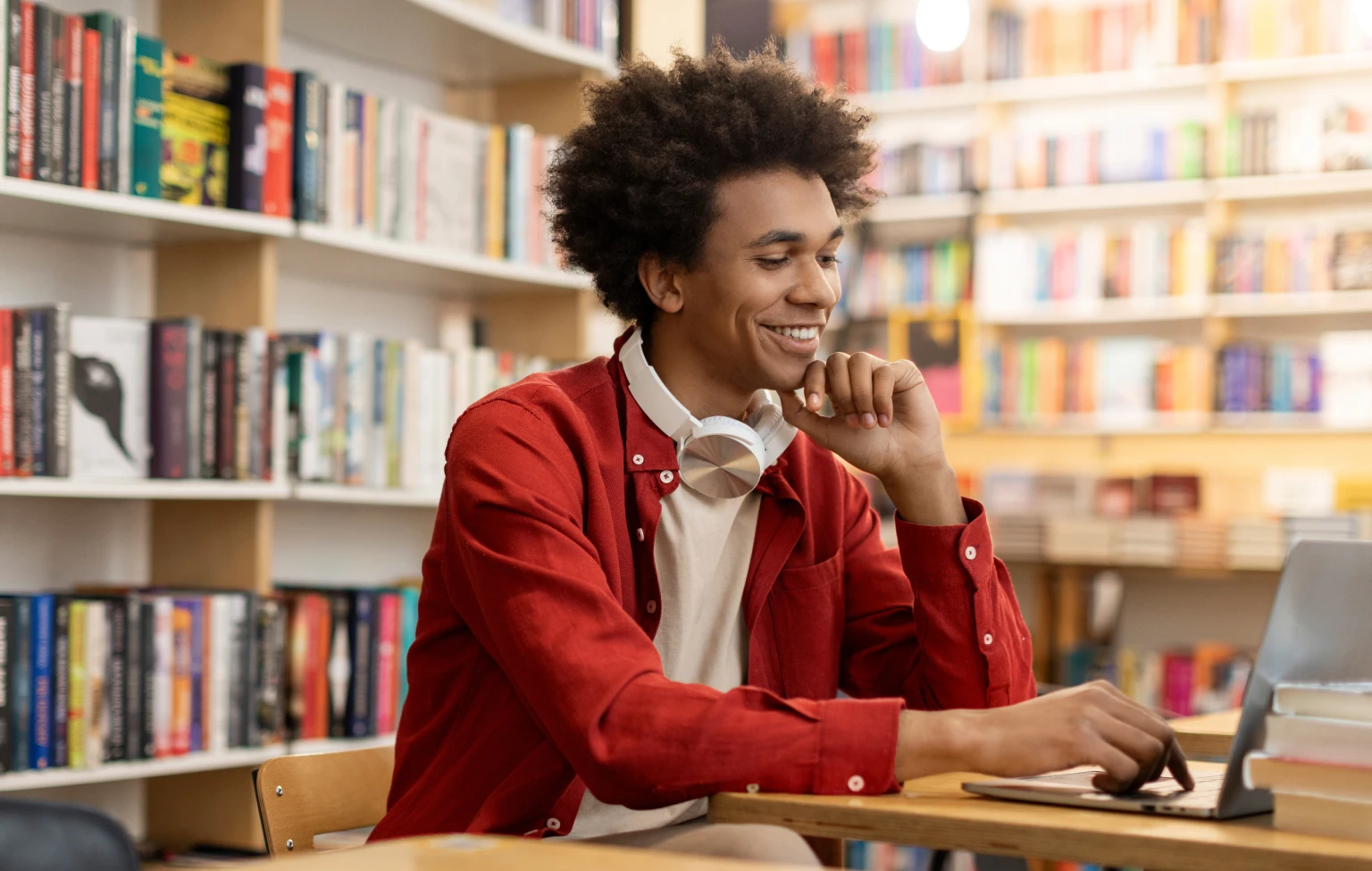 Student working on a laptop in a library while researching occupational therapy school applications.