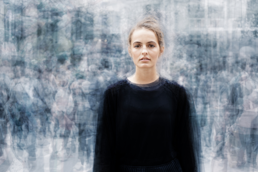 Woman standing still in a blurred city crowd, symbolizing the freeze response and feelings of stuckness many expats experience when moving abroad.