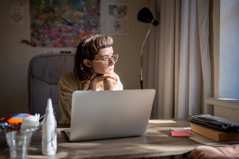 Woman sitting motionless at a desk in front of a laptop, symbolizing how the freeze response can look like procrastination but is not laziness.