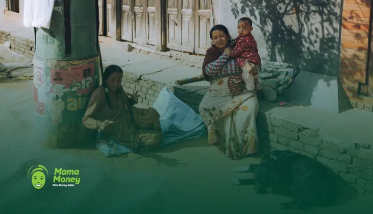 Nepali woman holding a child while sitting outside with another woman.