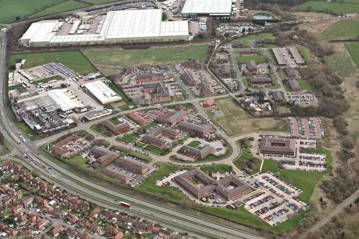 Aerial view of Gadbrook Park business park: office buildings, car parks and warehouses beside a main road.