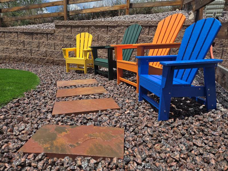 Arizona chopped flagstone walkway leading to colorful Adirondack chairs beside artificial turf in a Colorado Springs backyard retreat.