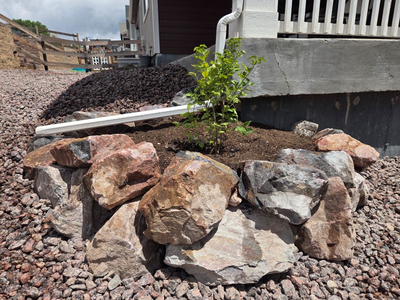 Natural boulder planter with newly installed lilac shrub and irrigation modifications in a low maintenance landscape project.