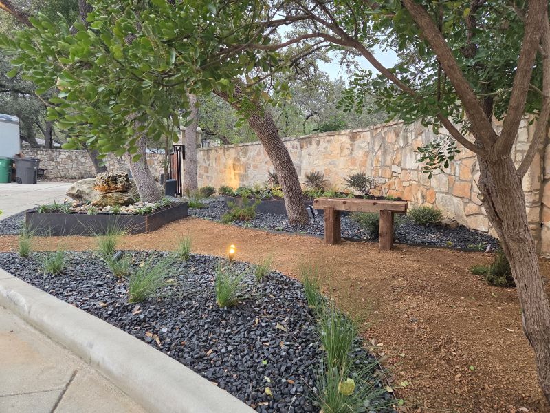 Landscape renovation featuring corten steel planter boxes, decomposed granite pathways, mature oak trees, custom lighting, and a bubbling fountain water feature.