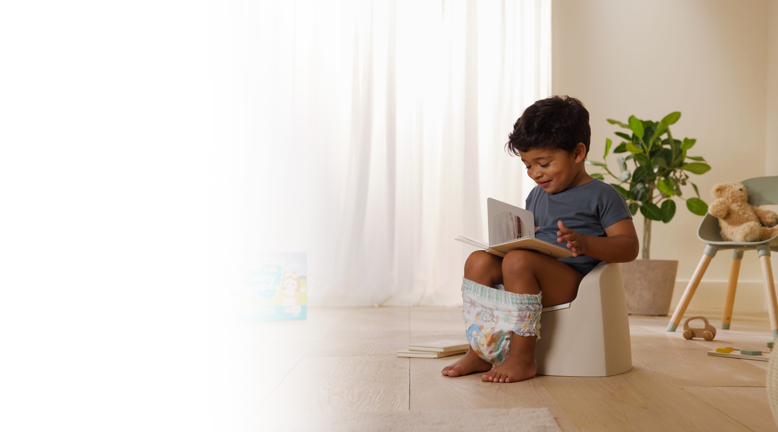 toddler sitting on potty whilst reading a book