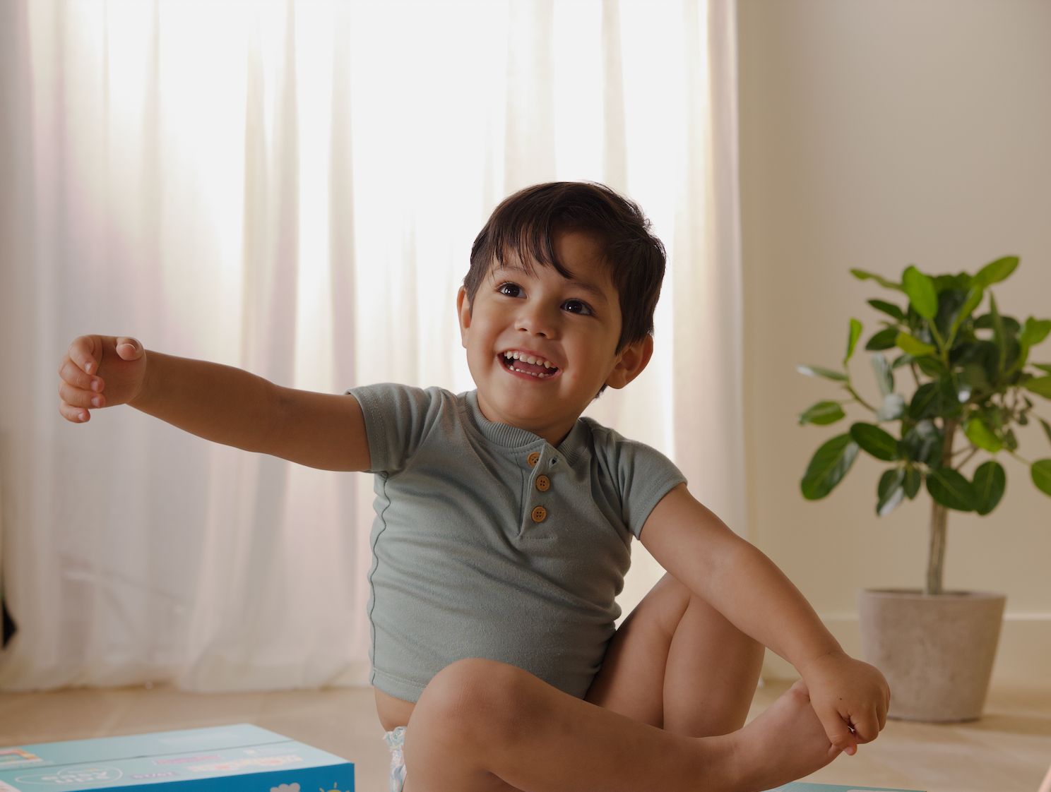 Baby smiling at camera in diaper and tshirt